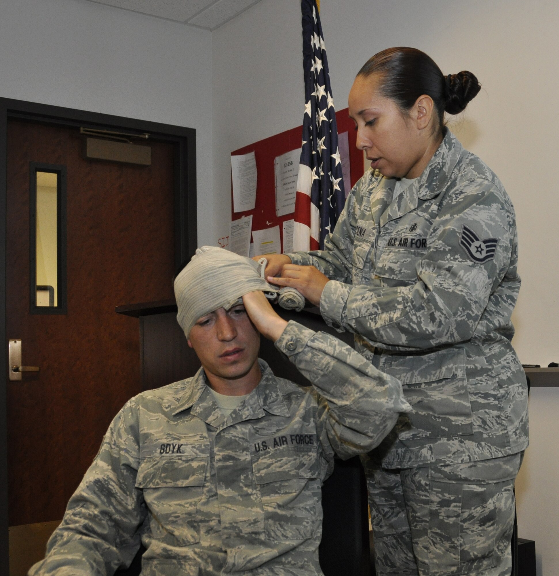 PETERSON AIR FORCE BASE, Colo., In preparation for the upcoming Operational Readiness Exercise, Staff Sgt. Alisa Pilena, a Self Aid Buddy Care instructor from the 21st Medical Group, demonstrates on Air Force Reserve Staff Sgt. Phillip Gdyk, a propulsion technician from the 302nd Maintenance Squadron, the correct application of an emergency bandage. The hands-on SABC classes were held here throughout the May Unit Training Assembly to ensure ORE participants are familiar and knowledgeable on the proper use of their Individual First Aid Kits. (U.S. Air Force photo/Tech. Sgt. Peter Dean)  
