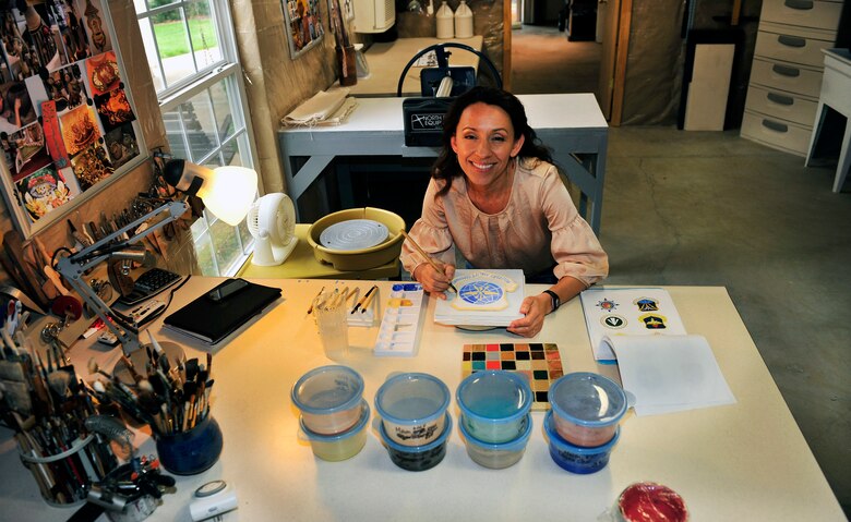 Artist Claudia Gullet paints a shield in her basement studio April 27, 2012. The shield is one of the 300 ceramic tiles that comprises the mural to be placed in the new Student Union on Scott Air Force Base, Ill. in June. (U.S. Air Force photo/ Staff Sgt. Stephenie Wade)