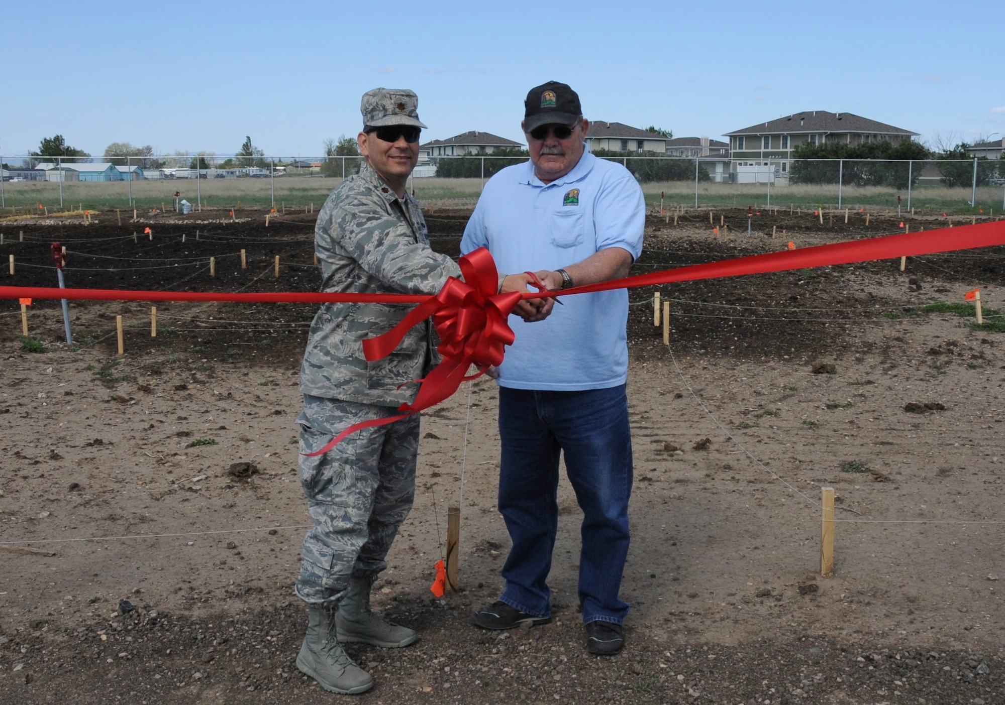 Maj. David Burnett, 28th Force Support Squadron commander, and Richard Nelson, 28th FSS Outdoor Recreation manager, cut a ribbon signifying the opening of the base garden plots at Ellsworth Air Force Base, S.D., May 8, 2012. The plots are located near Roosevelt Avenue near base housing and are available to rent through the outdoor recreation office. (U.S. Air Force photo by Airman 1st Class Anania Tekurio/Released)