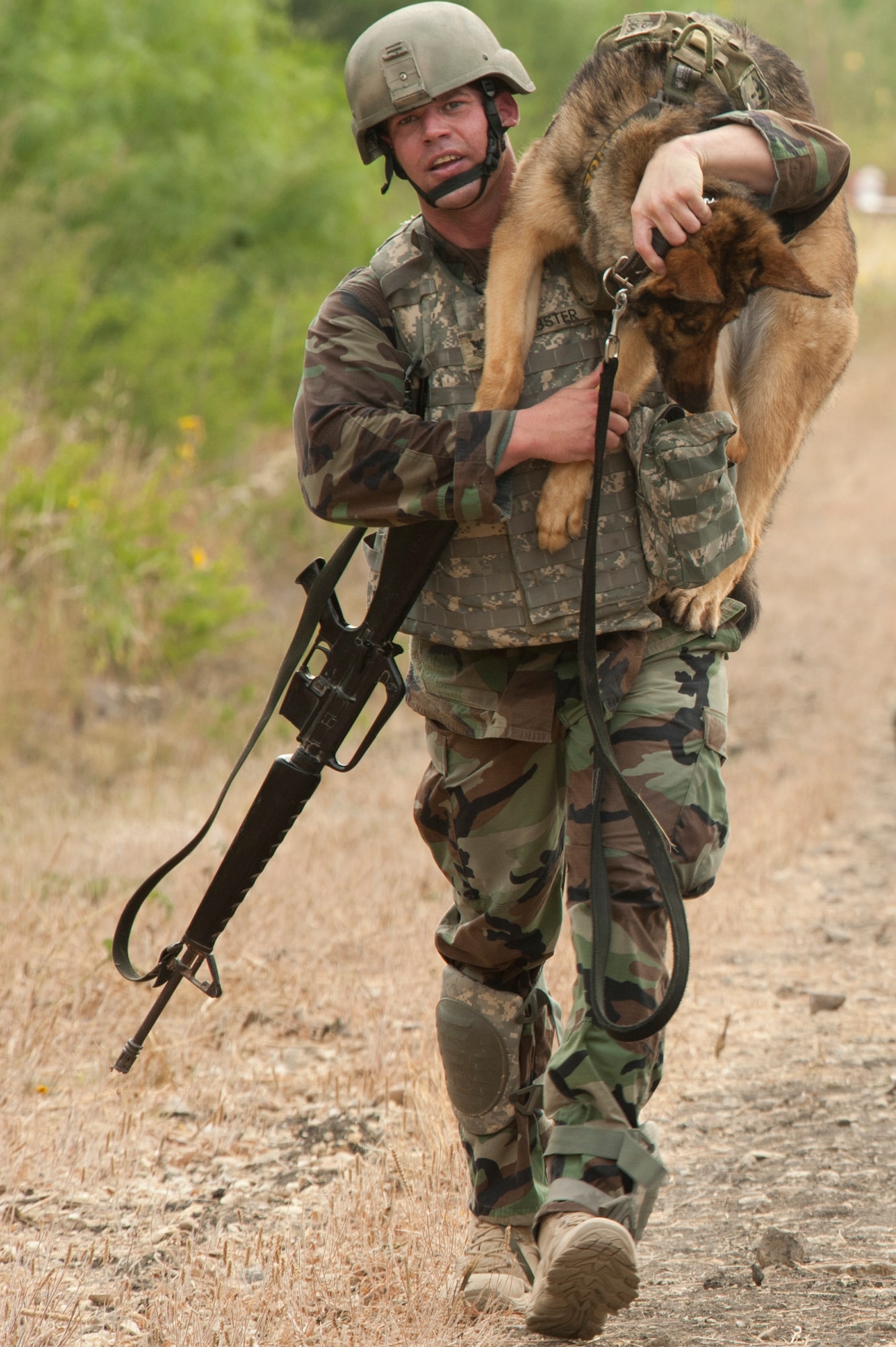 U.S. Navy Petty Officer 1st Class Nicholas Webster, master at arms and military working dog handler, carries Fergina, a 6-year-old patrol and explosives detection dog, as they compete during the Department of Defense Military Working Dog Trials at Joint Base San Antonio-Lackland, Texas, May 4, 2012. Military working dogs and their handlers from the Army, Navy, Air Force and Marines competed in the event. Webster is stationed at the Naval Air Station in Corpus Christi, Texas. (U.S. Air Force photo/Senior Airman Corey Hook)