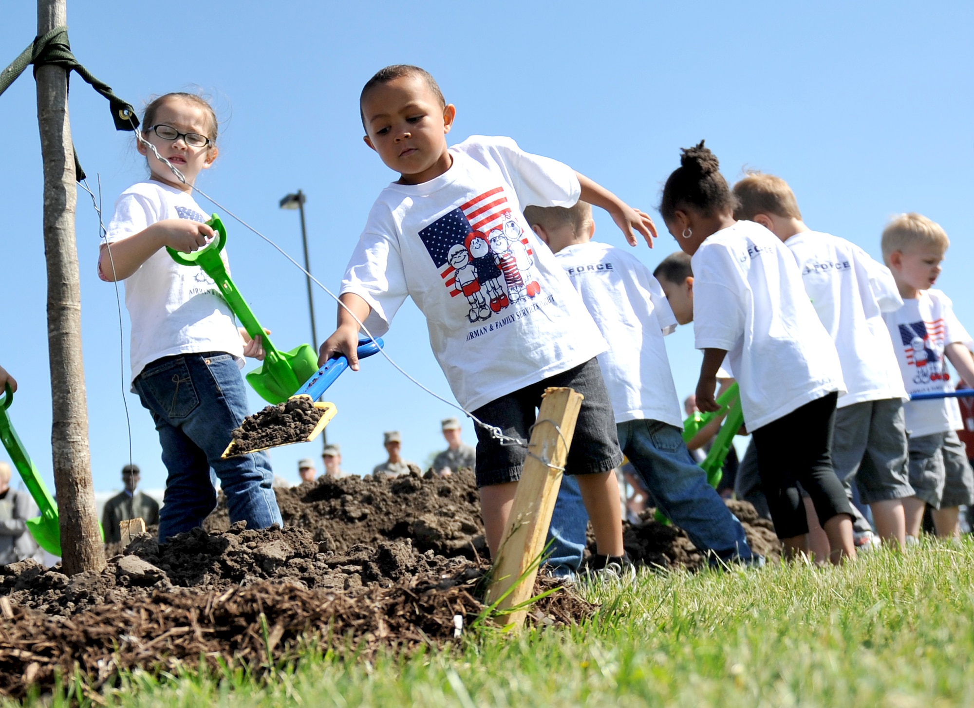 (Left to Right) Sydney Pontious looks over Kobly Johnson while he carefully places dirt around the tree with a little help from Maliyah Parker and Jack Duncan covering the newly planted Northern Red Oak tree in front of Child Development Center II on Offutt Air Force Base, Neb., April 26 in celebration of Arbor Day. Offutt has been named Tree City USA for the last 22 years by the Arbor Day Foundation. (U.S. Air Force photo by Jeff W. Gates/Released)