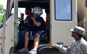 U.S. Army Sgt. Christopher Hitchman, 689th Rapid Port Opening Element forward distribution node NCOIC, helps local students explore the Heavy Expanded Mobility Tactical Truck Load Handling System during the Newport News Public Schools' George Green 41st Annual Special Education Field Day at Todd Stadium in Newport News, Va., May 1. In addition to a variety of competitions and games, 698th RPOE Soldiers provided tours of vehicles and equipment, and answered questions from students. (U.S. Army photo by Michelle Montieth/Released)