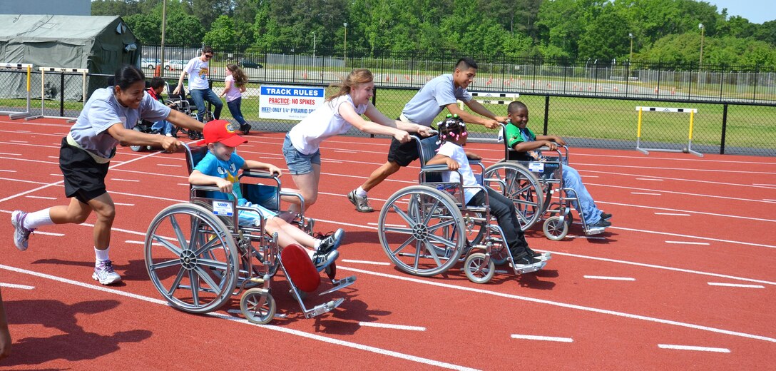U.S. Army Spc. Chandra Shrestha (left) and Pvt. Nick Deagueros (right-center), 689th Rapid Port Opening Element, join local students in a wheelchair race during the Newport News Public Schools' George Green 41st Annual Special Education Field Day at Todd Stadium in Newport News, Va., May 1. The Soldiers volunteered their time to help teachers interact with students in various events, including dribble relay, parachute pop, wheelchair races, hula-hoop ring toss, T-ball and obstacle courses. (U.S. Army photo by Michelle Montieth/Released)