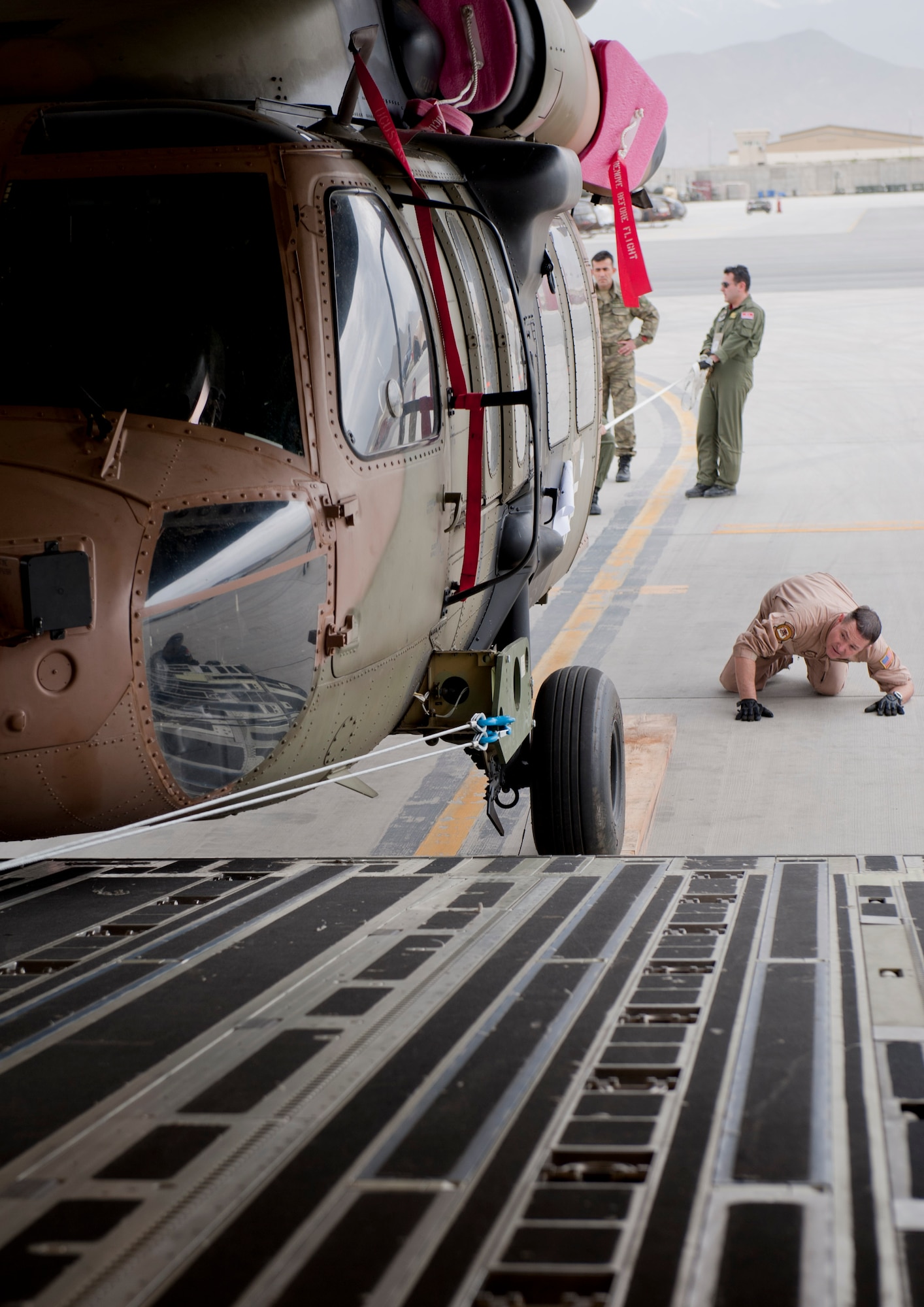Tech. Sgt. Michael Ferguson, 6th Airlift Squadron loadmaster, checks the underside of a Turkish air force UH-60 Black Hawk helicopter as it's unloaded from the back of a U.S. Air Force C-17 Globemaster III May 5, 2012, at Kabul International Airport, Afghanistan. The C-17 aircrew from Joint Base McGuire-Dix-Lakehurst, N.J., transported the helicopter to Kabul from Incirlik Air Base, Turkey. The joint support mission provided smooth delivery of the helicopter to replace one that crashed December 2011. (U.S. Air Force photo by Senior Airman Anthony Sanchelli/Released)