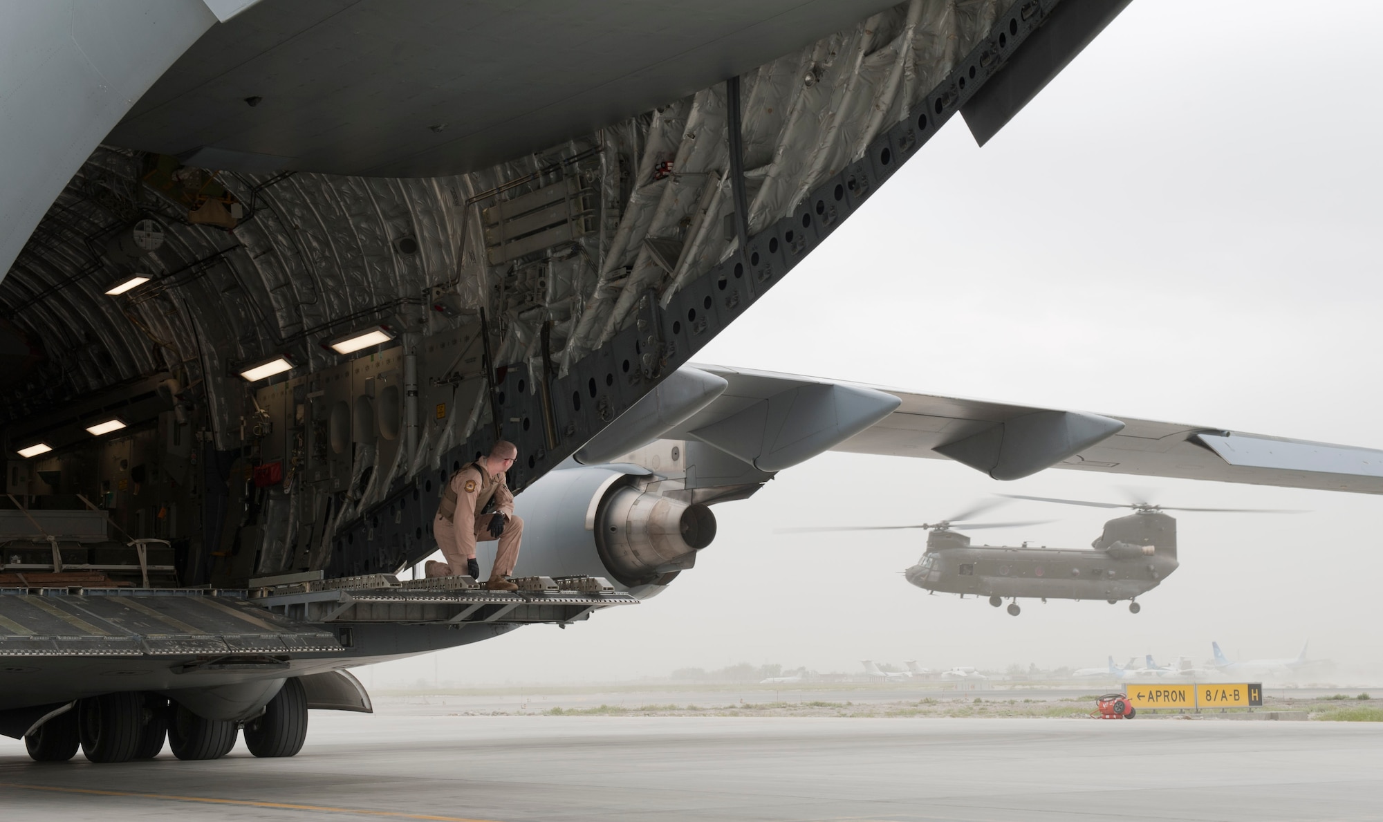 Staff Sgt. Micah Hackett, 6th Airlift Squadron loadmaster, watches a CH-47 Chinook helicopter from the back of a C-17 Globemaster III May 5, 2012, at Kabul International Airport, Afghanistan. The C-17 aircrew from Joint Base McGuire-Dix-Lakehurst, N.J., transported a Turkish air force UH-60 Black Hawk helicopter to Kabul from Incirlik Air Base, Turkey. The joint support mission provided smooth delivery of the helicopter to replace one that crashed December 2011. (U.S. Air Force photo by Senior Airman Anthony Sanchelli/Released)