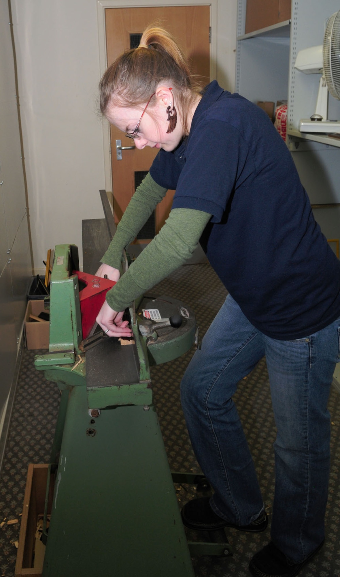 RAF MILDENHALL, England – Megan Wellentin, 100th Force Support Squadron Arts and Crafts Complex framer, uses a frame cutter to cut a leg of wood to make a picture frame May 4, 2012. After the customer chooses material for their custom frame, it is placed into a machine that cuts it to a 45 degree angle, which ensures the pieces of wood fit together perfectly to form a frame. (U.S. Air Force photo/Karen Abeyasekere)