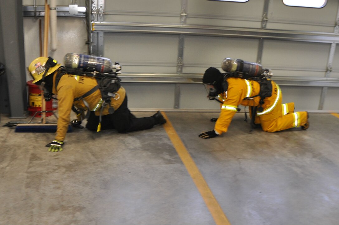 Agent Jeff Swearingen (right), with the Criminal Investigation Division of the Marine Corps Logistics Base Barstow Police Department, and Fire Prevention Officer Gabriel Hammett with the MCLB Barstow Fire Department, low crawl in SCBA gear as they would in a burning building to escape the smoke. Swearingen is learning about arson investigation in the only cross-training program of its type in Marine Corps Installations West.