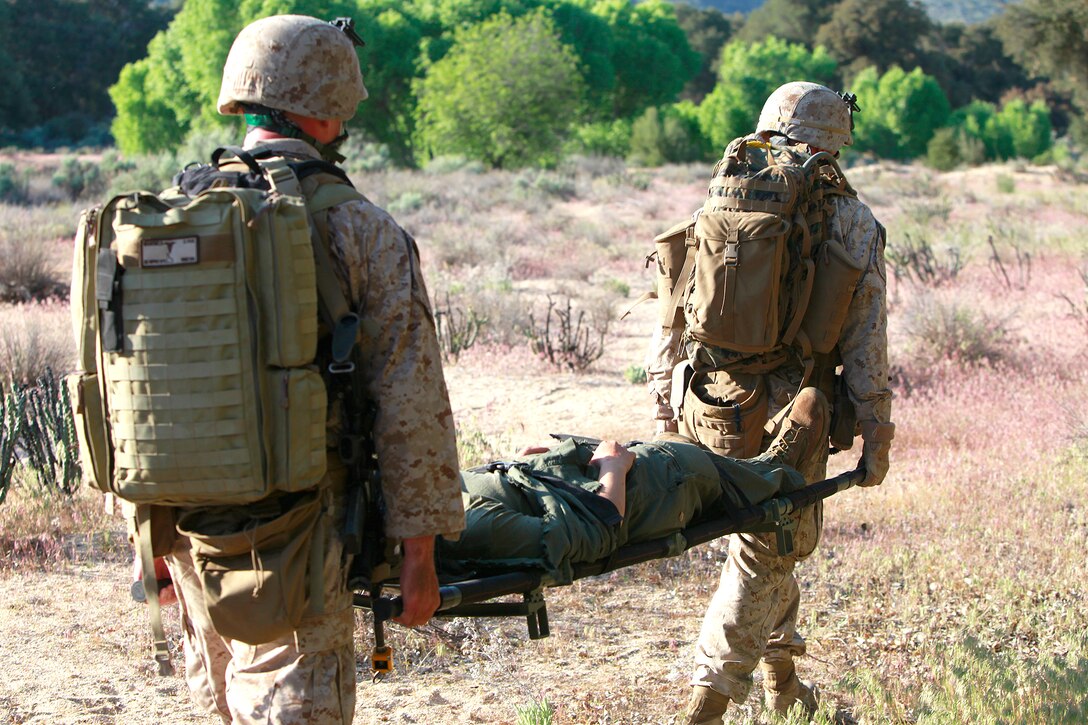 A Marine and a Navy corpsman with the Tactical Recovery of Aircraft and Personnel Platoon, 15th Marine Expeditionary Unit, carry Cpl. Brittany L. Jones back to the helicopter during training, here, May 9. Jones was playing the role of a downed pilot during a TRAP mission. The training was conducted as a part of the ground portion of Realistic Urban Training, an exercise designed to prepare the 15th MEU for their upcoming deployment scheduled for this fall. Jones, 25, is a native of Elizabethtown, N.C., and is a radio operator with the unit.