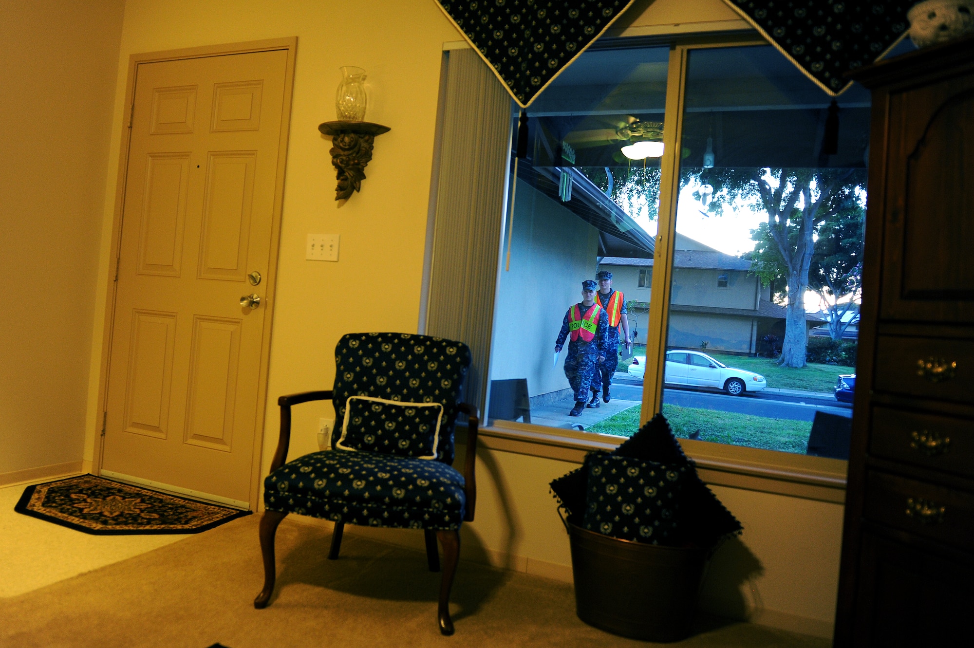 Petty Officer 2nd Class Tim Moss and Seaman Scott Meyer, Pearl Harbor harbor patrolmen, approach the home of Master Sgt. Tony Karpenko, 647th Logistics Readiness Squadron Fuels flight, on Hickam Field as they go door-to-door during Operation ENLIGHTEN II, May 9, where Airmen and Sailors went to more than 2,000 homes to hand out information about safety and security. In response to a rash of crimes ranging from petty theft to grand larceny, Joint Base Pearl Harbor-Hickam officials engaged residents in the anti-crime campaign. More than 120 volunteers went door-to-door during the blitz event. (U.S. Air Force photo/Staff Sgt. Mike Meares)