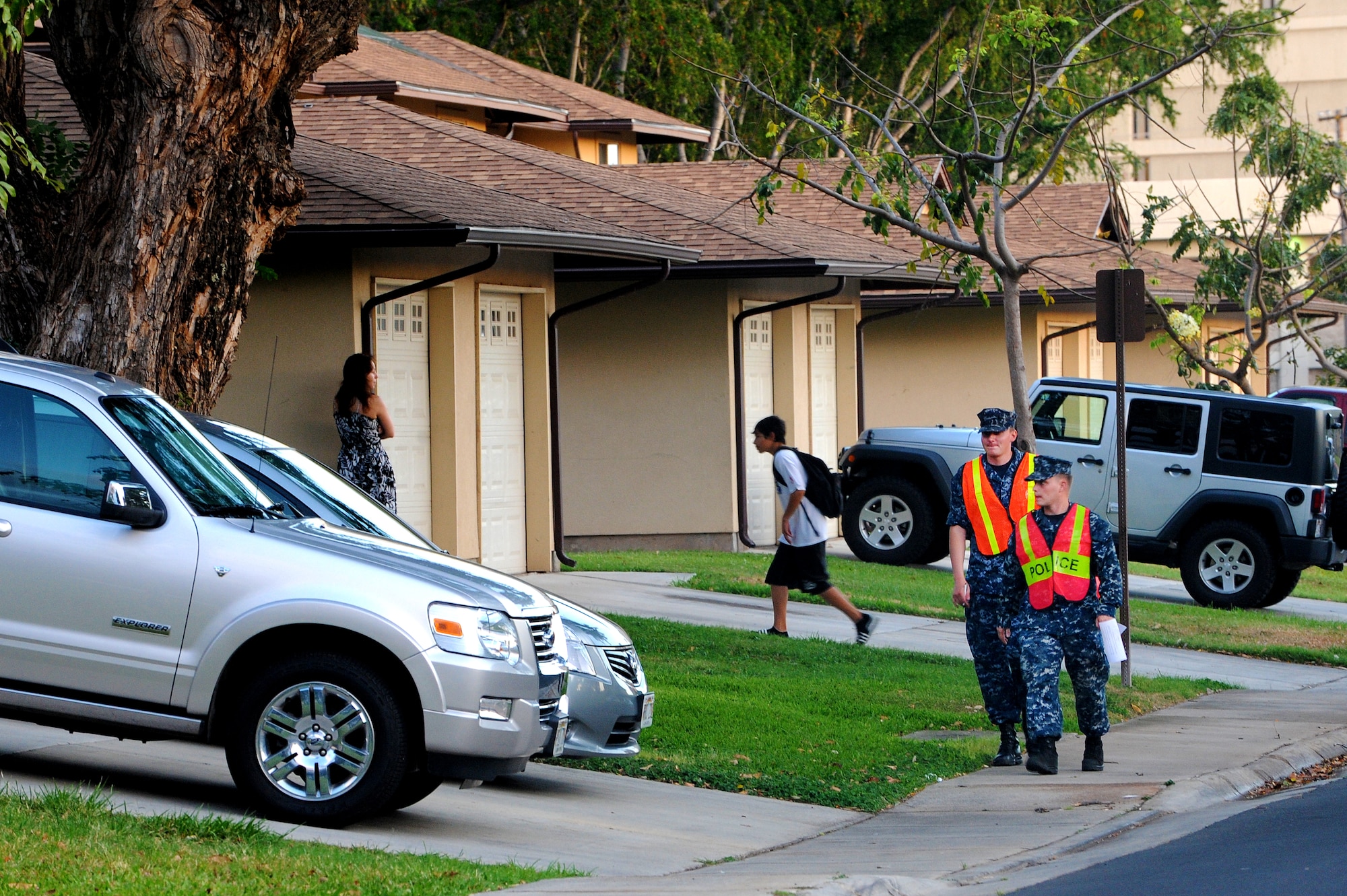 Petty Officer 2nd Class Tim Moss and Seaman Scott Meyer, Pearl Harbor harbor patrolmen, walk down Ohana Nui Circle on Hickam Field as they go door-to-door during Operation ENLIGHTEN II, May 9, where Airmen and Sailors went to more than 2,000 homes to hand out information about safety and security. In response to a rash of crimes ranging from petty theft to grand larceny, Joint Base Pearl Harbor-Hickam officials engaged residents in the anti-crime campaign. More than 120 volunteers went door-to-door during the blitz event. (U.S. Air Force photo/Staff Sgt. Mike Meares)