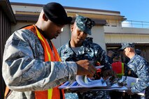 Tech. Sgt. Sylvester Lawrence, 647th Security Forces Squadron, and Petty Officer 2nd Class Timothy Magee, Navy Security Department patrolman, review a map of a housing area on Ford Island where the team went door-to-door to hand out information about safety and security during Operation ENLIGHTEN II, May 9. In response to a rash of crimes ranging from petty theft to grand larceny, Joint Base Pearl Harbor-Hickam officials engaged residents in the anti-crime campaign. More than 120 volunteers knocked on more than 2,000 doors spreading during the blitz event. (U.S. Air Force photo/Staff Sgt. Mike Meares)