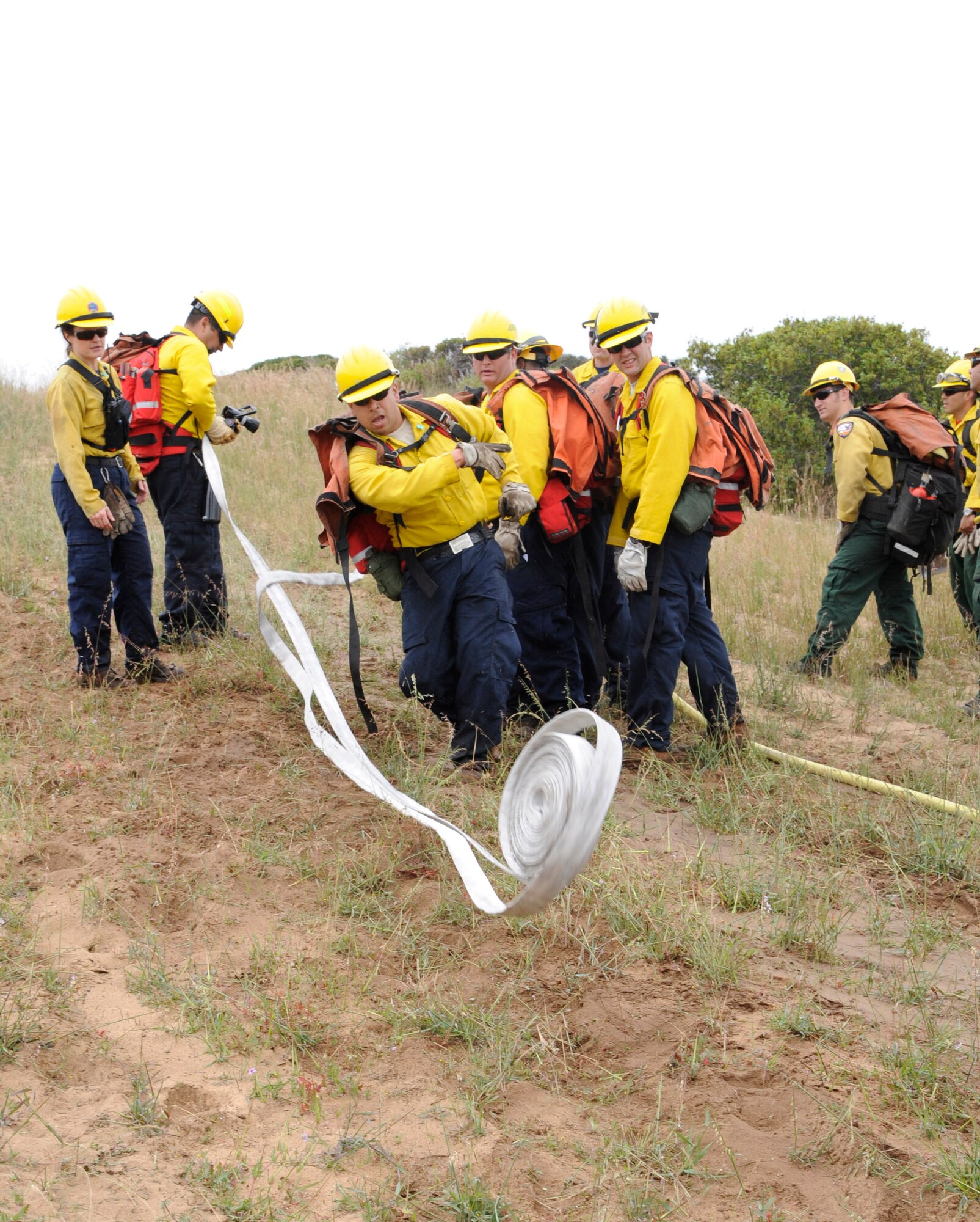 VANDENBERG AIR FORCE BASE, Calif. -- Vince Montejo, a wild land firefighting student, rolls out his hose extension to add more length to the existing fire hose here Tuesday, May 1, 2012. Firefighters carry extra hoses to continuously and safely extinguish fires deep in the brush. 