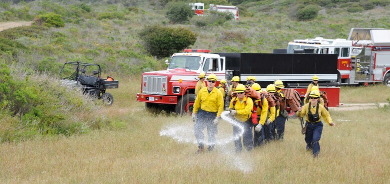 VANDENBERG AIR FORCE BASE, Calif. -- Evan Bolles and Michelle Birchfield, 30th Civil Engineer Squadron Hot Shots instructors, walk a group of firefighting students up a firebreak teaching progressive hose lay techniques here Tuesday, May 1, 2012. The Hot Shots tackle tough terrain and extinguish flames while armed with chain saws, axes, shovels and rakes.  