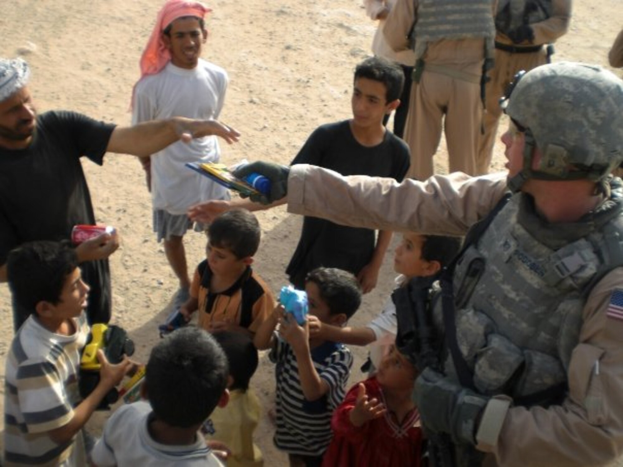 Tech. Sgt. Gregory Podobensky distributes candy to Iraqi children while deployed to Iraq in 2008. Podobensky received a Combat Action Badge for his actions following the detonation of an explosively formed projectile, May 5. (Courtesy Photo)