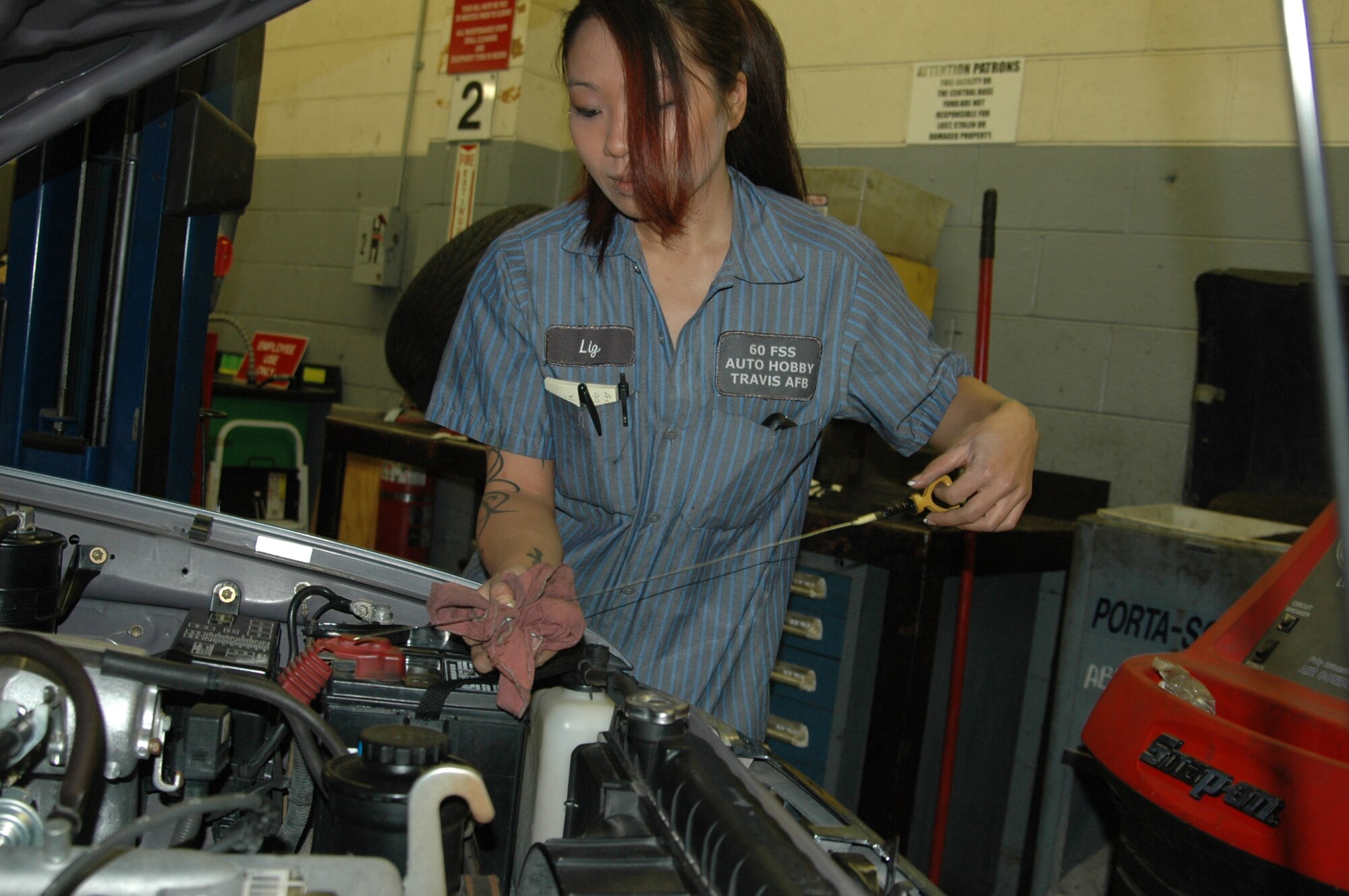 Elizabeth Mainwaring, Travis Auto Hobby Shop tools and parts attendant checks a car’s oil level  April 27 at the Auto Hobby Shop. (U.S. Air Force photo/ Tyler Grimes)