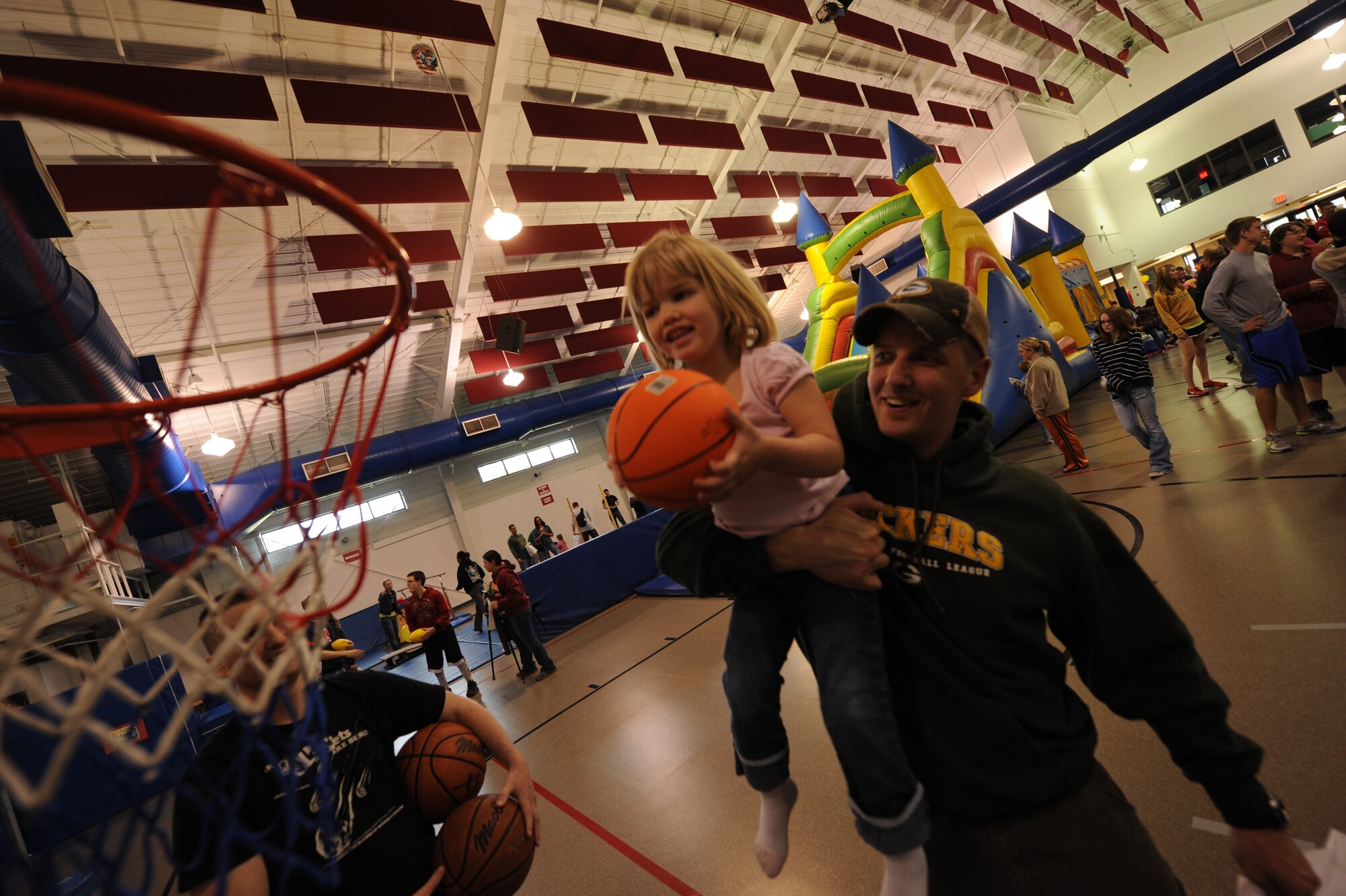 Staff Sgt. Todd Viney holds his daughter, Cadence, as she gets ready to throw a basketball through the net during the School Fair on May 8, 2012, on Grand Forks Air Force Base, N.D.
