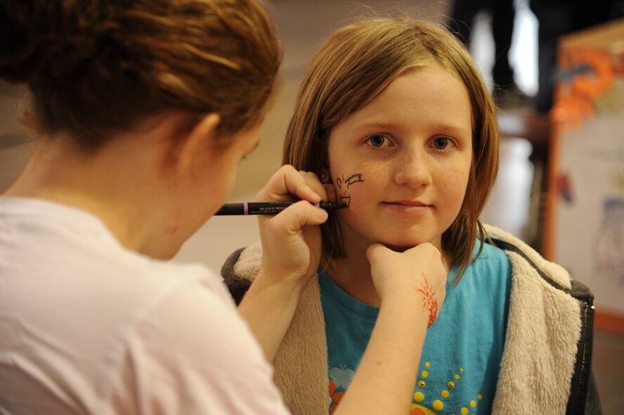 Twelve-year-old Ali Hitchcock sits patiently as A1C Vivienne Cassidy paints her face at the School Carnival in Liberty Square on May 8, 2012, on Grand Forks Air Force Base, N.D. (U.S. Air Force photo/Tim Flack)