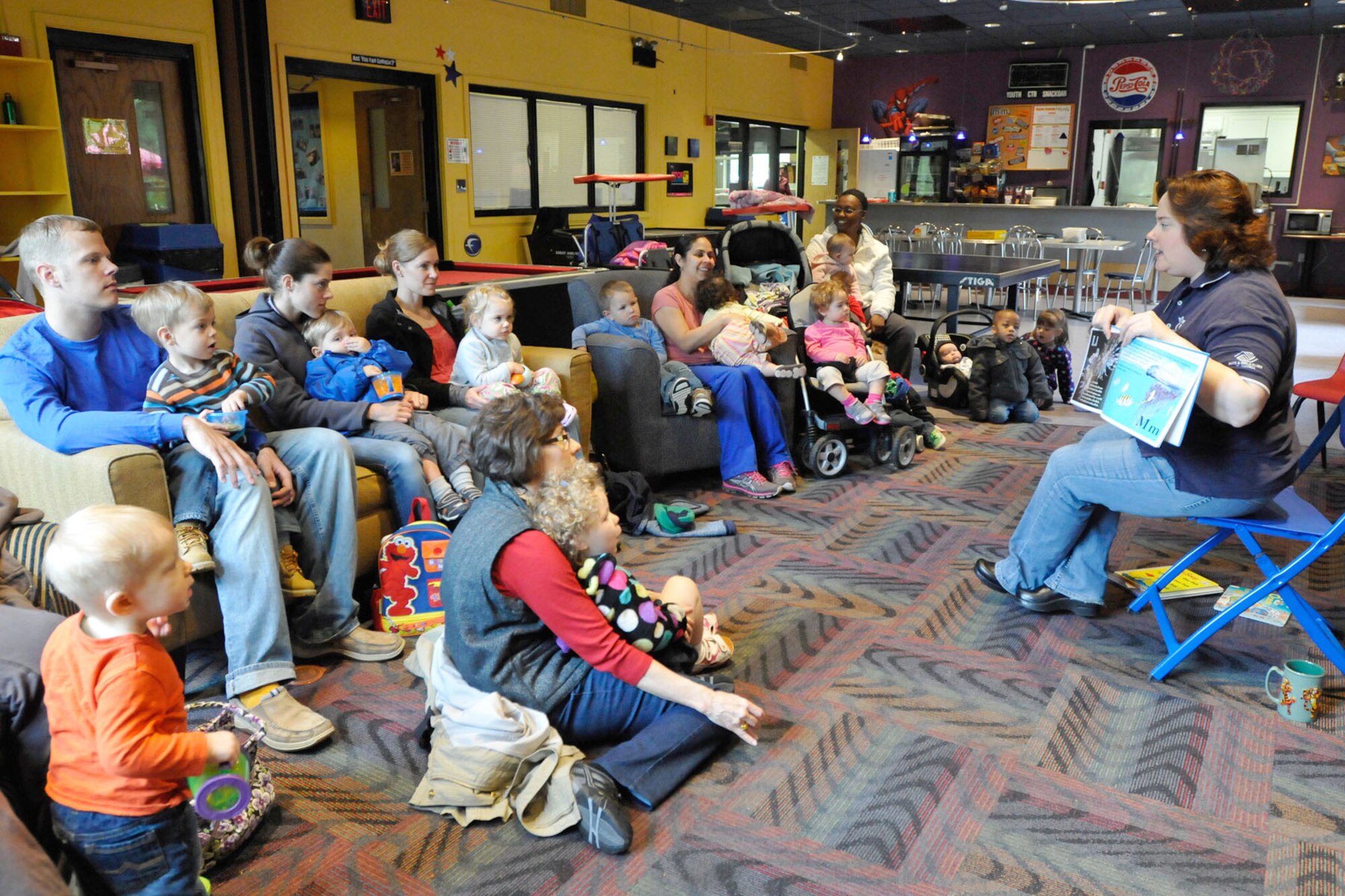 HANSCOM AIR FORCE BASE, Mass. - Julie Frederick (right), a program director from the Youth Center, reads to preschool-aged children and their parents at the Youth Center May 2. Last week marked the beginning of storytime at its new location at the Youth Center. Several other changes to base services will be occurring in the coming months as part of the Air Force’s Global Base Support initiative. (U.S. Air Force photo by Linda LaBonte Britt)