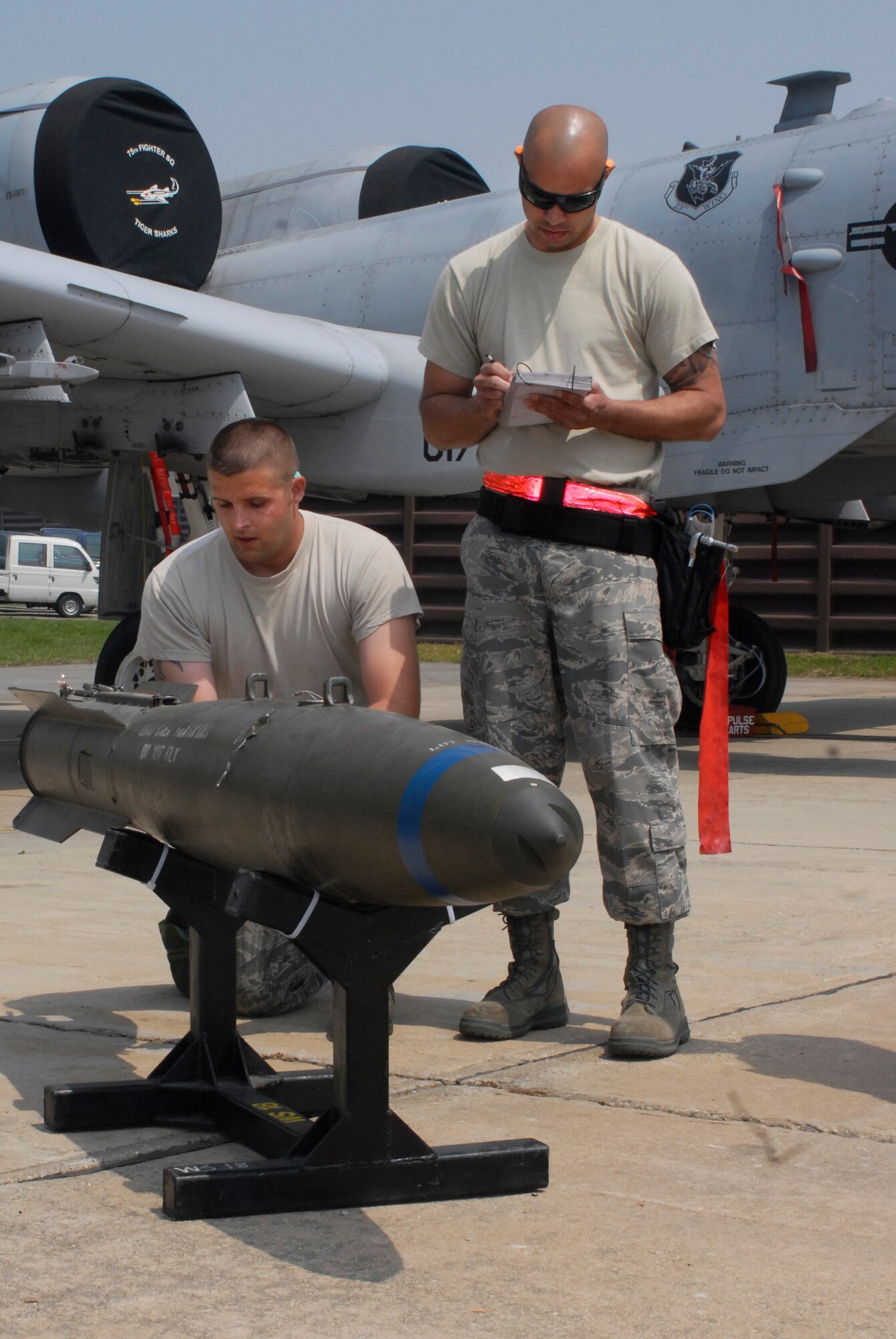 Senior Airman Brannon Ledbetter, 75th Aircraft Maintenance Unit weapons loader, is graded by an evaluator while preparing a Mk-82 500-pound bomb during a weapon loading competition at Osan Air Base, Republic of Korea, May 5, 2012. (U.S. Air Force photo/Tech. Sgt. Eric Petosky)