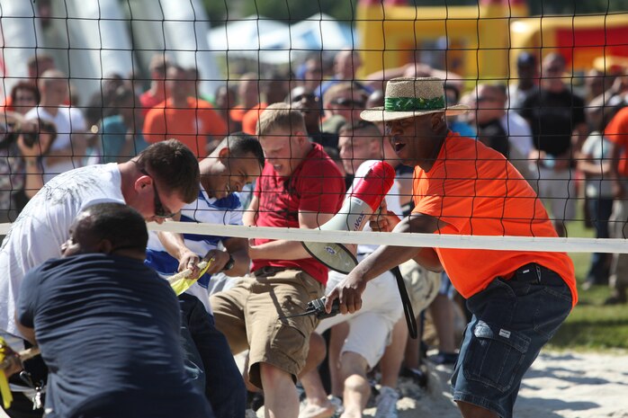 Master Sgt. Andre S. Mayhue (right), the current operations chief for 2nd Marine Logistics Group, observes and narrates as Marines and sailors compete in a tug-of-war event during a 2nd MLG family day aboard Camp Lejeune, N.C., May 11, 2012. Family members also had the opportunity to enjoy the multiple inflatable attractions, as well as static displays of some of the Marine Corps’ trucks, heavy equipment and helicopters. The event was organized to commemorate the military spouse appreciation day.