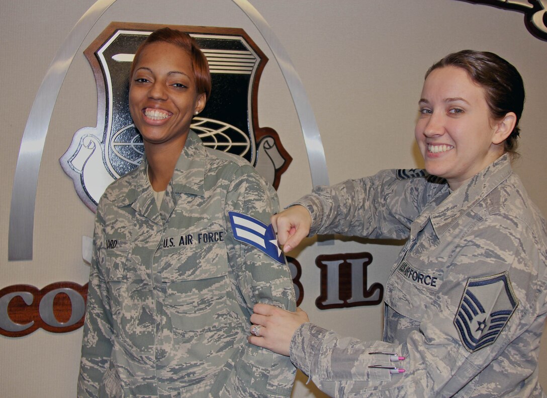 Master Sgt. Becky Velazquez gives Airman First Class Brittany Ford the customary punch to the arm, marking her promotion.  Ford was promoted to her new rank earlier this month. Velazquez and Ford are both assigned to the 932nd Force Support Squadron and work in the customer service section.  (U.S. Air Force photo/Tech. Sgt. Dan Oliver)  