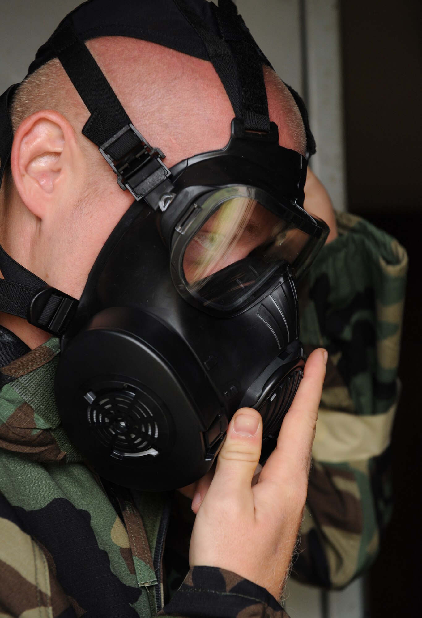 A Barksdale Airman dons his gas mask during an Ability to Survive and Operate exercise on Barksdale Air Force Base, La., May 11. When donning a gas mask, Airmen must perform certain checks to make sure it fits properly.  Some of the checks include adjusting the straps and performing a seal test to ensure there are no leaks. (U.S. Air Force photo/Airman 1st Class Benjamin Gonsier)(RELEASED)
