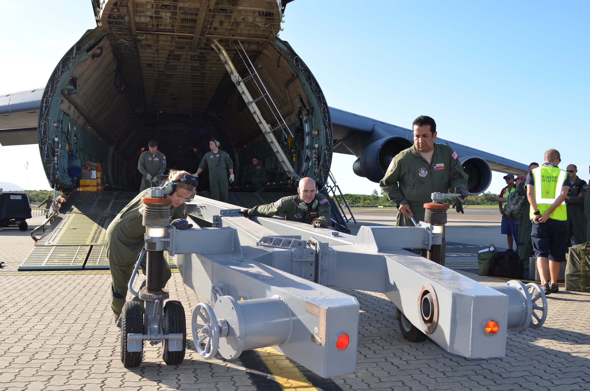 From left to right: 68th Airlift Squadon loadmasters, Senior Airman Katy Mackey, Master Sgt. Kevin Foerster, Senior Master Sgt. Dustin Burleson, Airman First Class Brandon Stone, and Master Sgt. Alfonso Cervantes unload an aircraft tow bar off C-5A Galaxy upon arrival to Cairns, Australia on May 5, 2012. The tow bar was used airport officials to move the Air Force's largest transport aircraft in place to load the U.S. Coast Guard's HH-65C Dolphin helicopter. (U.S. Air Force Photo/Maj. Tim Wade)