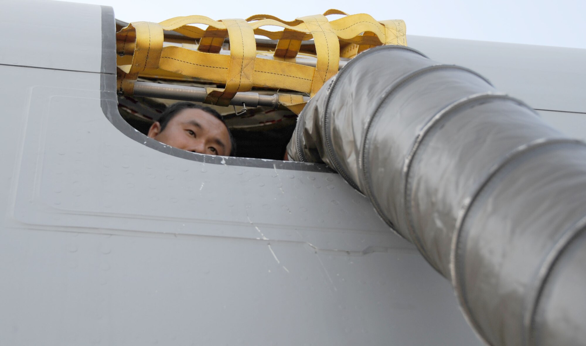 MACDILL AIR FORCE BASE, Fla. – Peeking from the hatch of a KC-135 Stratotanker is Staff Sgt. Stephen Shin, a crew chief with the 927th Air refueling Wing.  Shin helped to install the air conditioning pipe into the aircraft for an upcoming static display.  Temperatures can reach well over 100 degrees in the summertime; 40 degree air conditioning makes a more comfortable environment for visiting guests to tour the aircraft.  (Official U.S. Air Force photo/Staff Sgt. Shawn Rhodes)