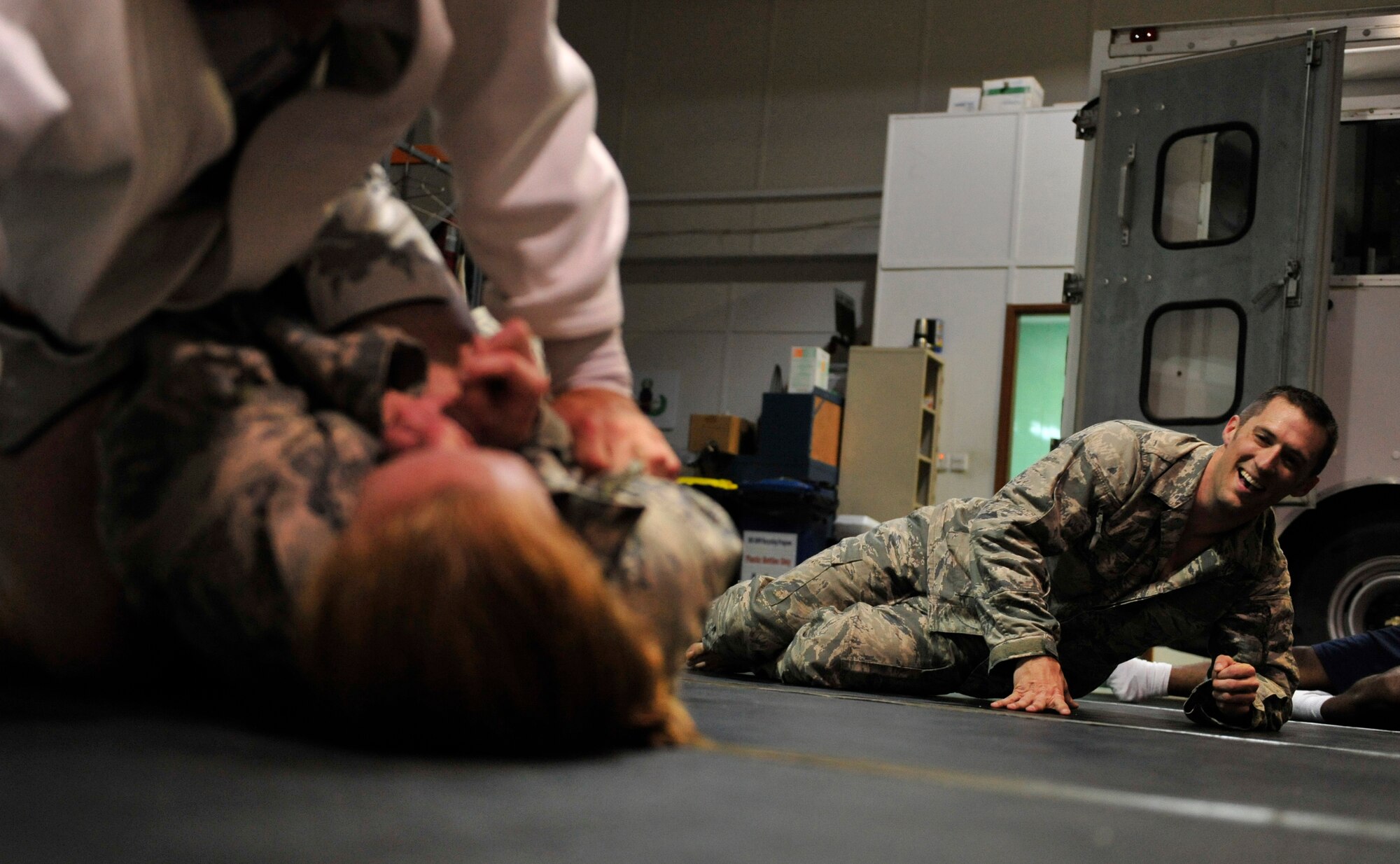 SOUTHWEST ASIA-U.S. Air Force Staff Sgt. James A. Bennett, Level III Combative trainer, looks on while Staff Sgt. Anthony Walling and Staff Sgt. Jessica Lafo roll during combatives training in Southwest Asia May 6, 2012. The three sergeants are explosive ordnance disposal technicians with the 380th Expeditionary Civil Engineer Squadron. Members of the EOD flight use combatives as part of their training routine to stay in top physical shape. (U.S. Air Force photo/Staff Sgt. Sara Csurilla)