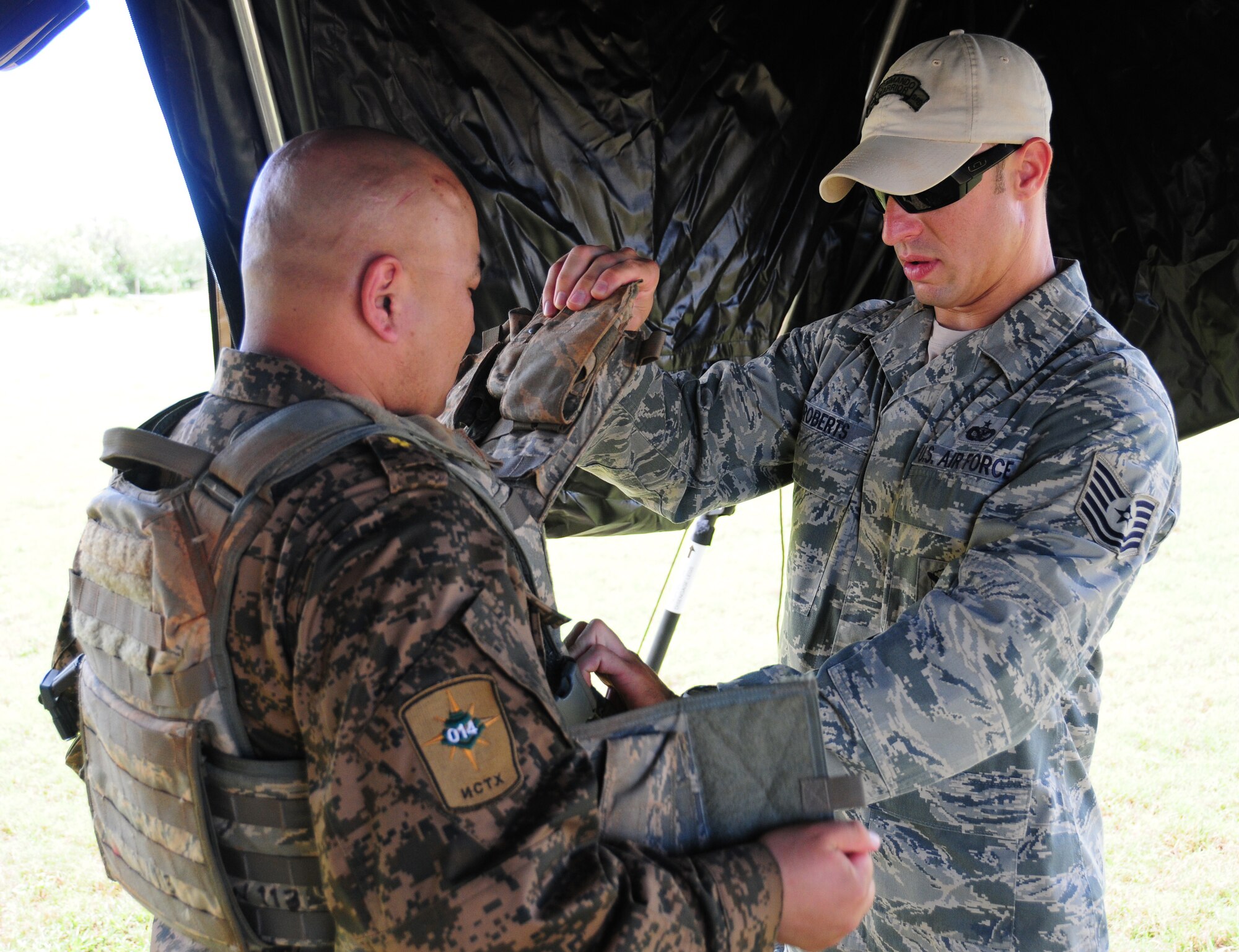 Staff Sgt. Nicholas Roberts, 736th Security Forces Squadron assists a host nation representative in putting on tactical gear during the Pacific Defender subject matter expert exchange May 10. Pacific Defender allows partner Nations to exchange ideas and methods of training within the Pacific region and showcases U.S. commitment to its allies and partners in the Asia-Pacific region. (U.S. Air Force photo by Senior Airman Jeffrey Schultze/released)