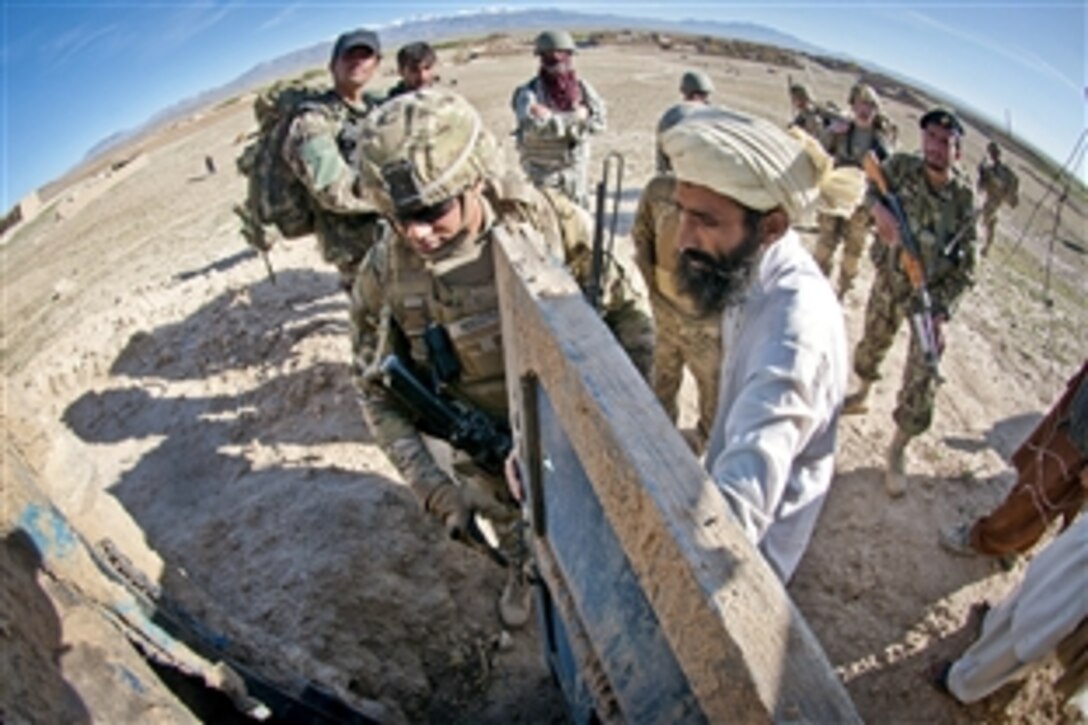 An Afghan villager unlocks the door of a suspected homemade explosives factory for U.S. Army Spc. Timothy Rodgers in Afghanistan's Ghazni province, May 4, 2012. Rodgers is assigned to the 82nd Airborne Division’s 1st Brigade Combat Team.