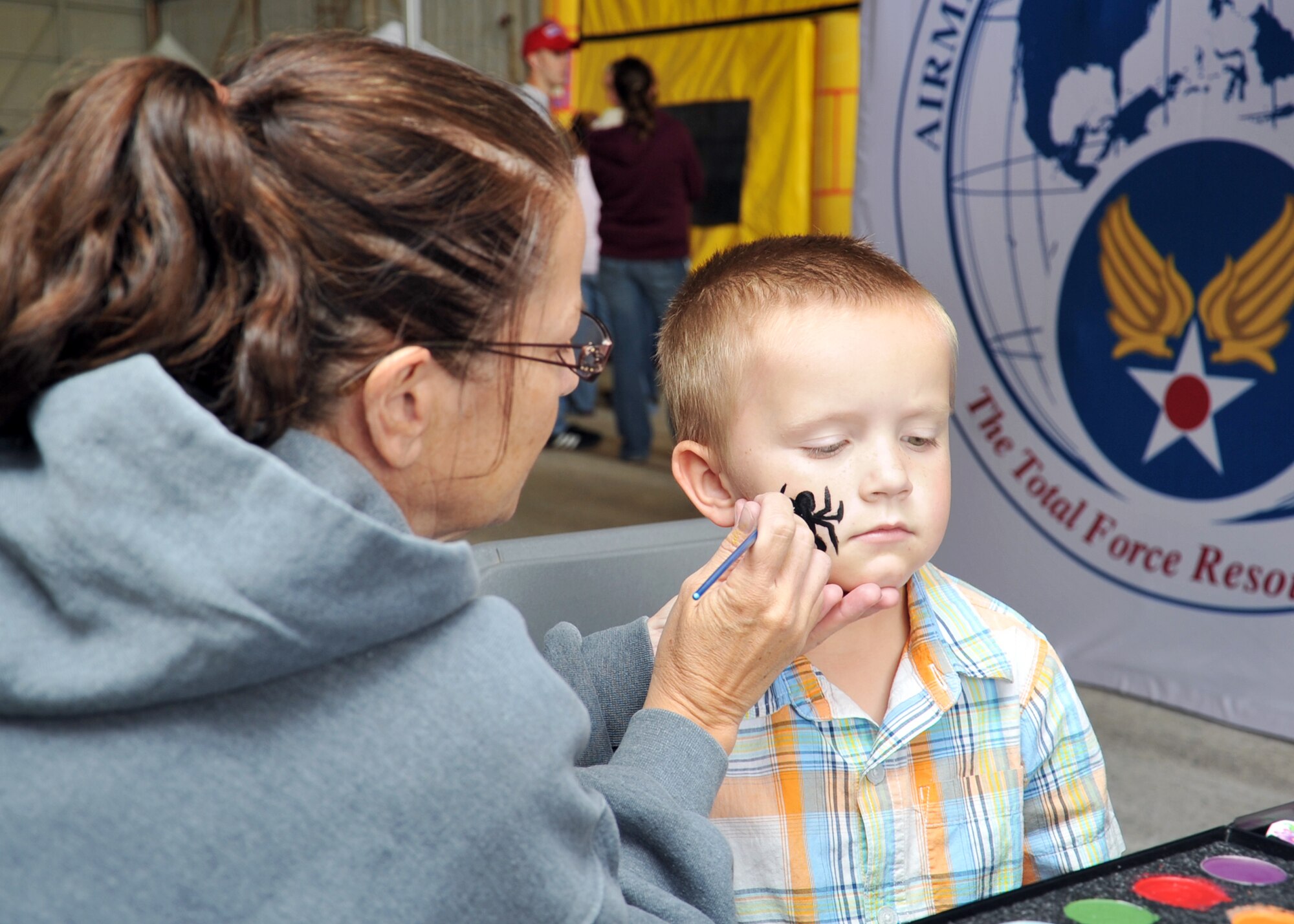 ALTUS AIR FORCE BASE, Okla. – Jackie Williams, 97th Force Support Squadron Airmen and Family Readiness consultant, paints a spider on Caden Holle’s face during the Open House, here May 12, 2012. Altus AFB hosted the open house event, which offered food booths, static aircraft displays, games and demonstrations throughout the day, to show appreciation to the local community. (U.S. Air Force photo by Senior Airman Leandra D. Stepp / 97th Air Mobility Wing Public Affairs / Released)