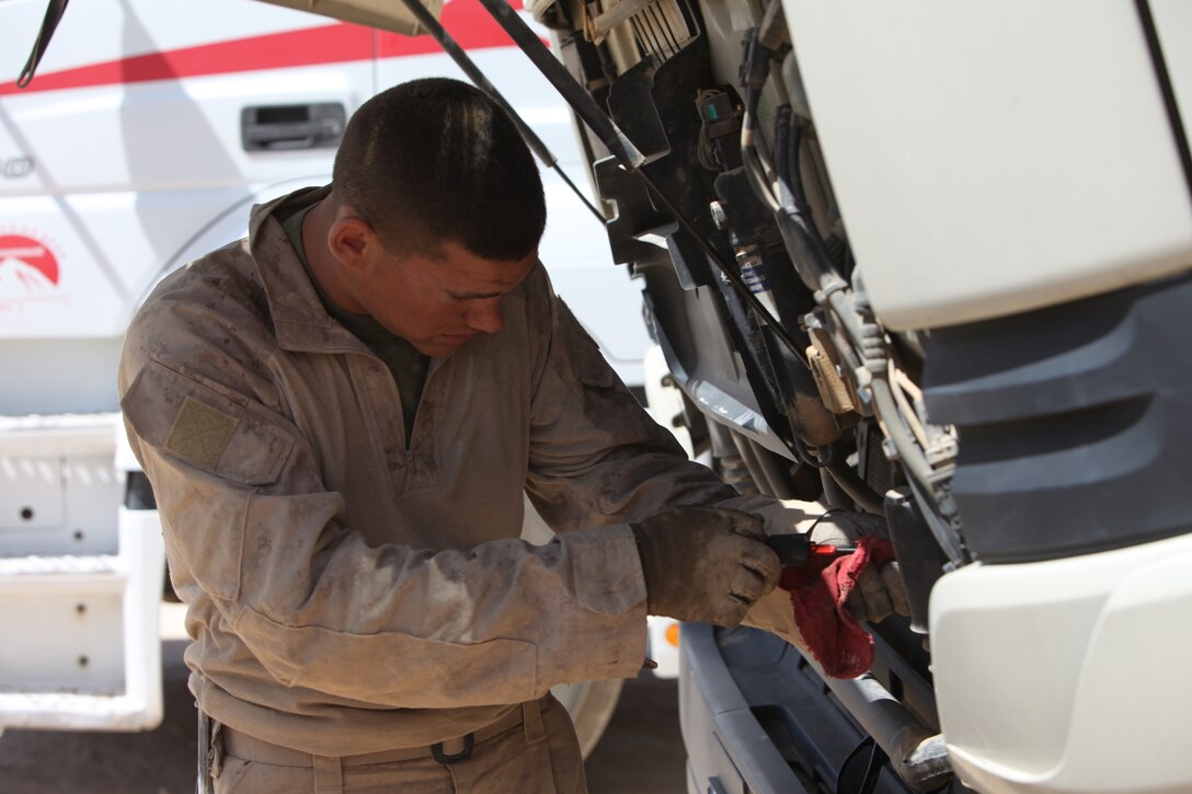A motor transport mechanic, General Support Motor Transport Company, 1st Maintenance Battalion (-) (Reinforced), 1st Marine Logistics Group (Forward), checks the fluids of a truck during a vehicle inspection prior to a fuel run in Helmand Province, Afghanistan, May 13. During the inspection, the mechanics check all aspects of the truck to minimize issues that may arise during the trip.