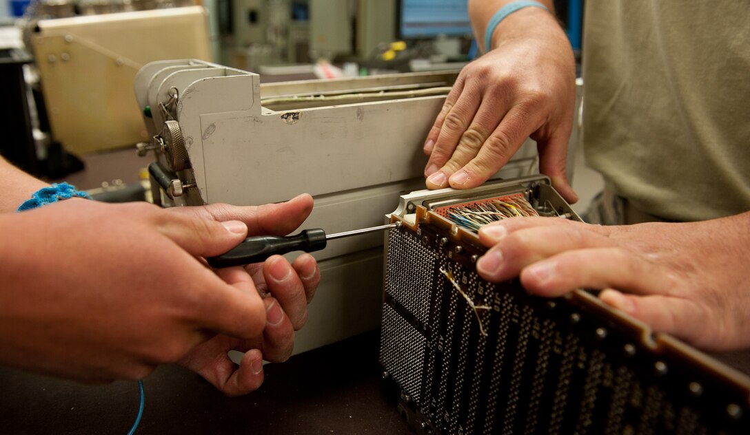 Senior Airmen Steven Rosales (left) and David Fisher, 28th Maintenance Squadron avionics technicians, unscrew a circuit board from a central integrated test system data acquisition unit motherboard to replace guide pin sleeves at the digital analog video avionics shop on Ellsworth Air Force Base, S.D., May 9, 2012. The unit samples, processes and distributes subsystem test data to allow the computer and navigation systems of the B-1 bomber to work properly. (U.S. Air Force photo by Airman 1st Class Kate Thornton/Released)