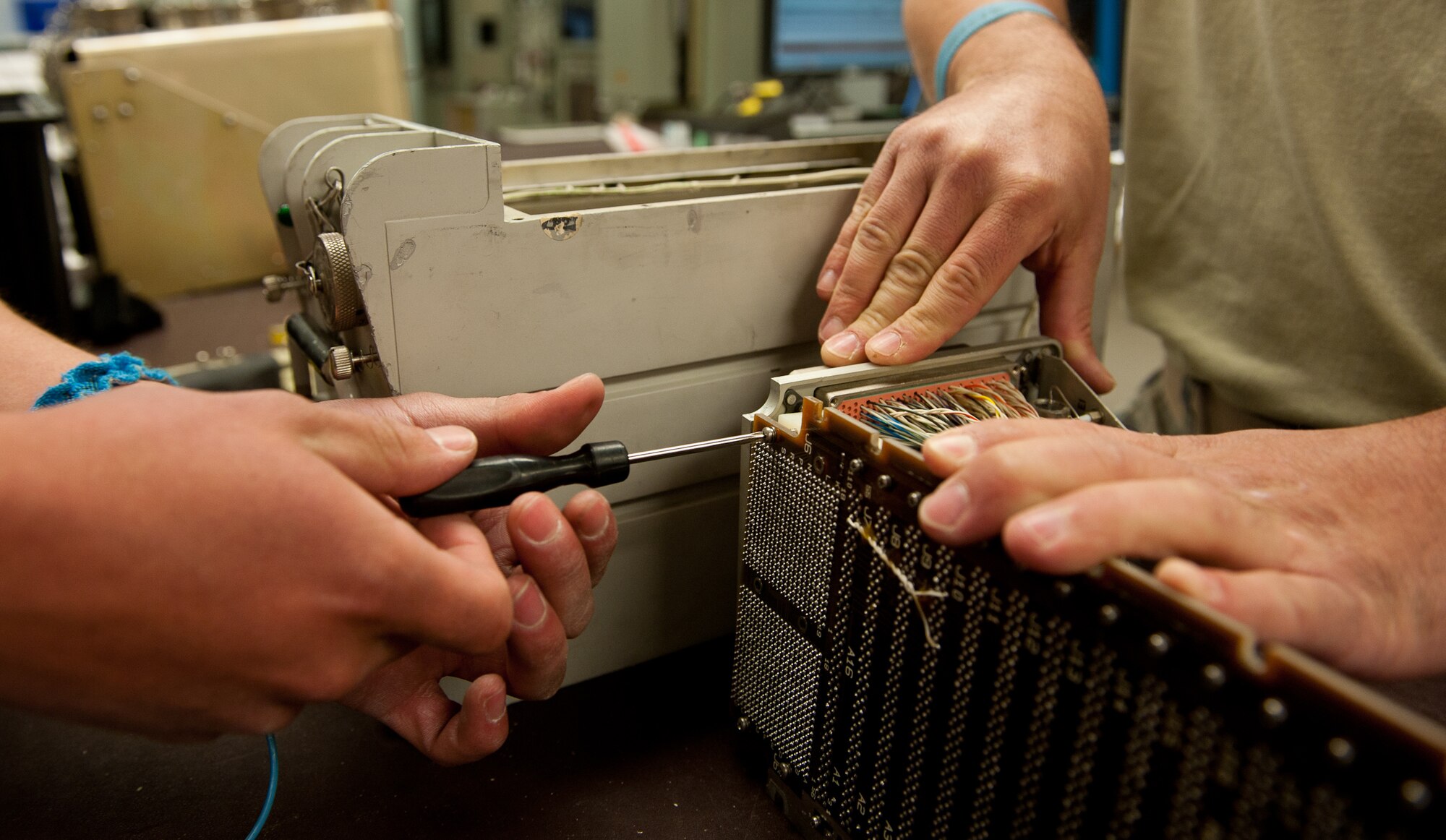Senior Airmen Steven Rosales (left) and David Fisher, 28th Maintenance Squadron avionics technicians, unscrew a circuit board from a central integrated test system data acquisition unit motherboard to replace guide pin sleeves at the digital analog video avionics shop on Ellsworth Air Force Base, S.D., May 9, 2012. The unit samples, processes and distributes subsystem test data to allow the computer and navigation systems of the B-1 bomber to work properly. (U.S. Air Force photo by Airman 1st Class Kate Thornton/Released)