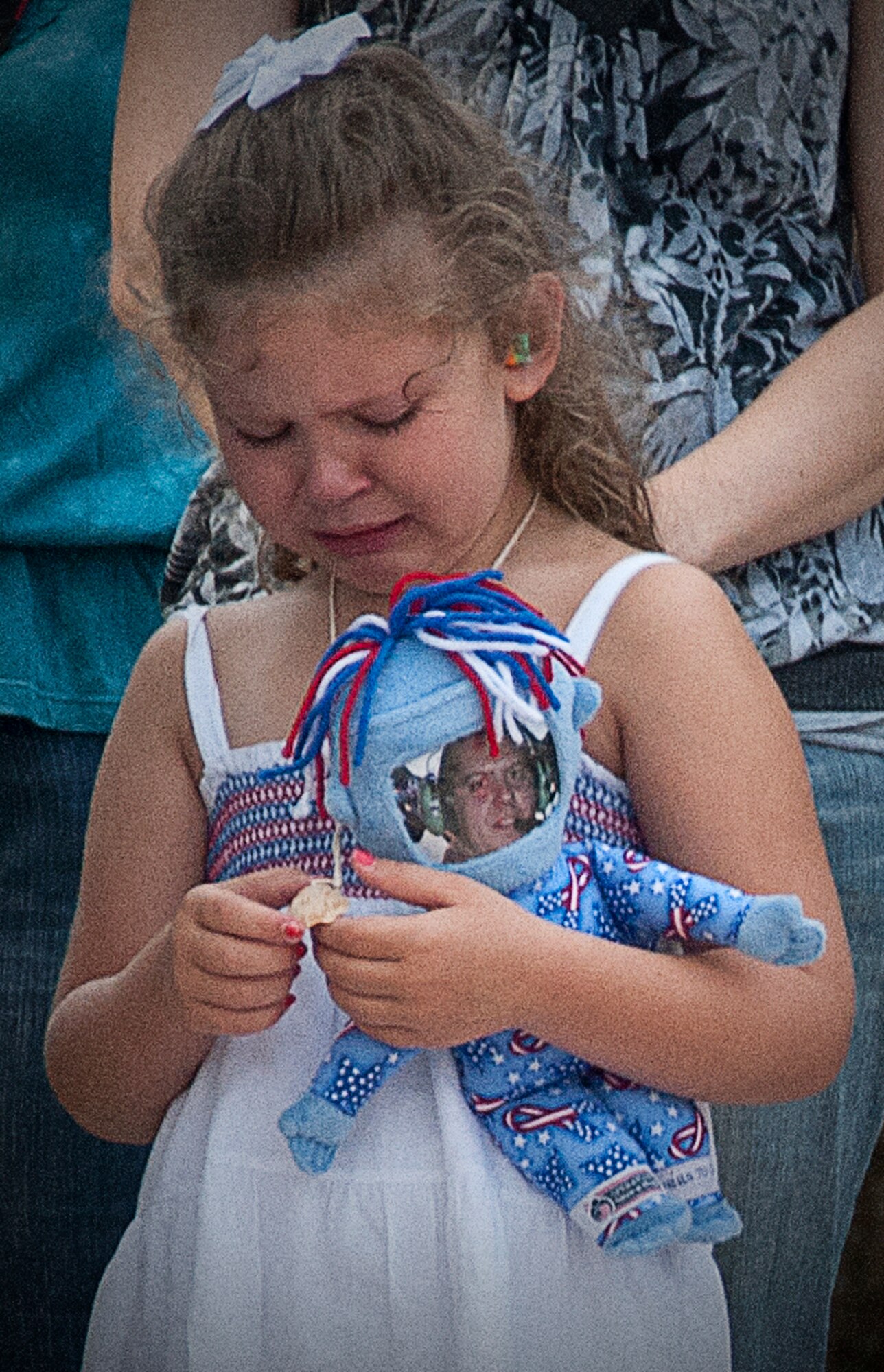 Lilly Vogel holds her dolly with her daddy's photo as she and other 345th Airlift Squadron family members await the departure of their loved ones. Lilly's dad, Staff Sgt. Andrew Vogel, and approximately 50 members of the 345th AS and 815th AS deployed May 9 to support contingency operations in Southwest Asia. (U.S. Air Force photo by Maj. Heather Newcomb)