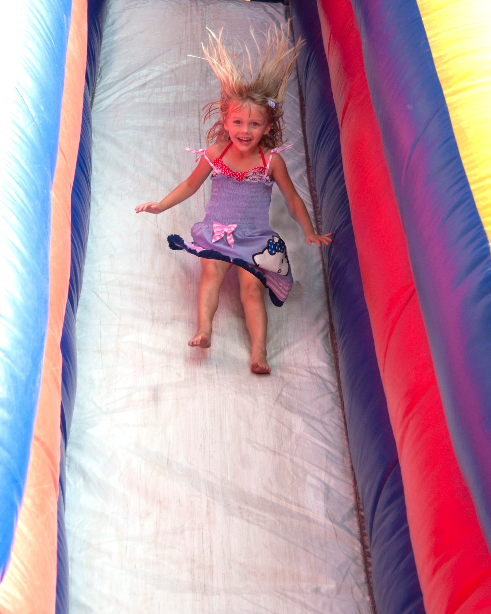 Reese Bulliard, daughter of Capt. Tiffanie Bulliard, is all smiles as she comes down the inflatable slide set up at the 403rd Wing's Family Day May 5. (U.S. Air Force photo illustration by Maj. Heather Newcomb)