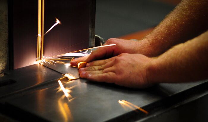 Nicholas Peeples, an aircraft metals technology journeyman with the 437th Maintenance Squadron out of Joint Base Charleston, S.C., grinds a piece of titanium May 9, 2012. Peeples worked in the aircraft metals technology shop as an Airman, but recently retired and now works as a civil servant. (U.S. Air Force photo/Airman 1st Class Dennis Sloan)