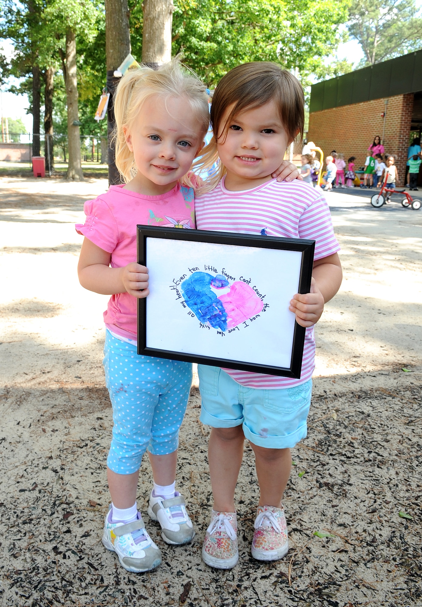 Issy Sanford and Olivia Mills, both 3, hold a framed handprint heart at the child development center on Seymour Johnson Air Force Base, N.C., May 10, 2012. The children made the art in daycare and gave their mothers the handprint hearts as a Mother’s Day gift. Issy is the daughter of Master Sgt. Alison Sanford, 911th Air Refueling Squadron. Olivia is the daughter of Senior Airman Ryan Mills, assigned to the 336th Aircraft Maintenance Unit. (U.S. Air Force photo/Airman 1st Class Aubrey Robinson/Released)
