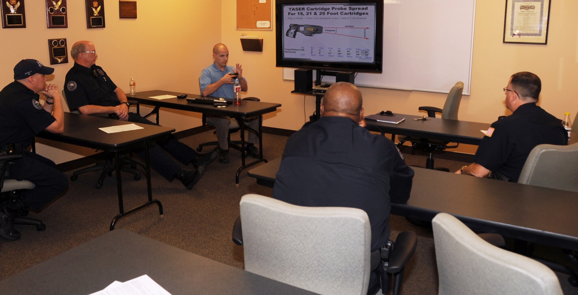 ALTUS, Okla. -- Joshua Leach, 97th Security Forces Squadron lead investigator and master Taser instructor, talks with members of the City of Altus Police Department about how the probes in a Taser spread once the trigger is pulled, during a Taser training May 9, 2012 at the Altus Police Department. Leach is a certified master Taser instructor and recently re-certified 27 Altus police officers, which saved the city approximately $10,000. (U.S. Air Force photo by Airman 1st Class Kenneth W. Norman / Released / 97th Air Mobility Wing Public Affairs)