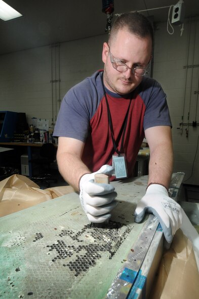 Technician Jason Thompson, with the 551st CMMXS, removes damaged aluminum honeycomb core from a B1 horizontal stabilizer tip. (Air Force photo by Dave Faytinger)