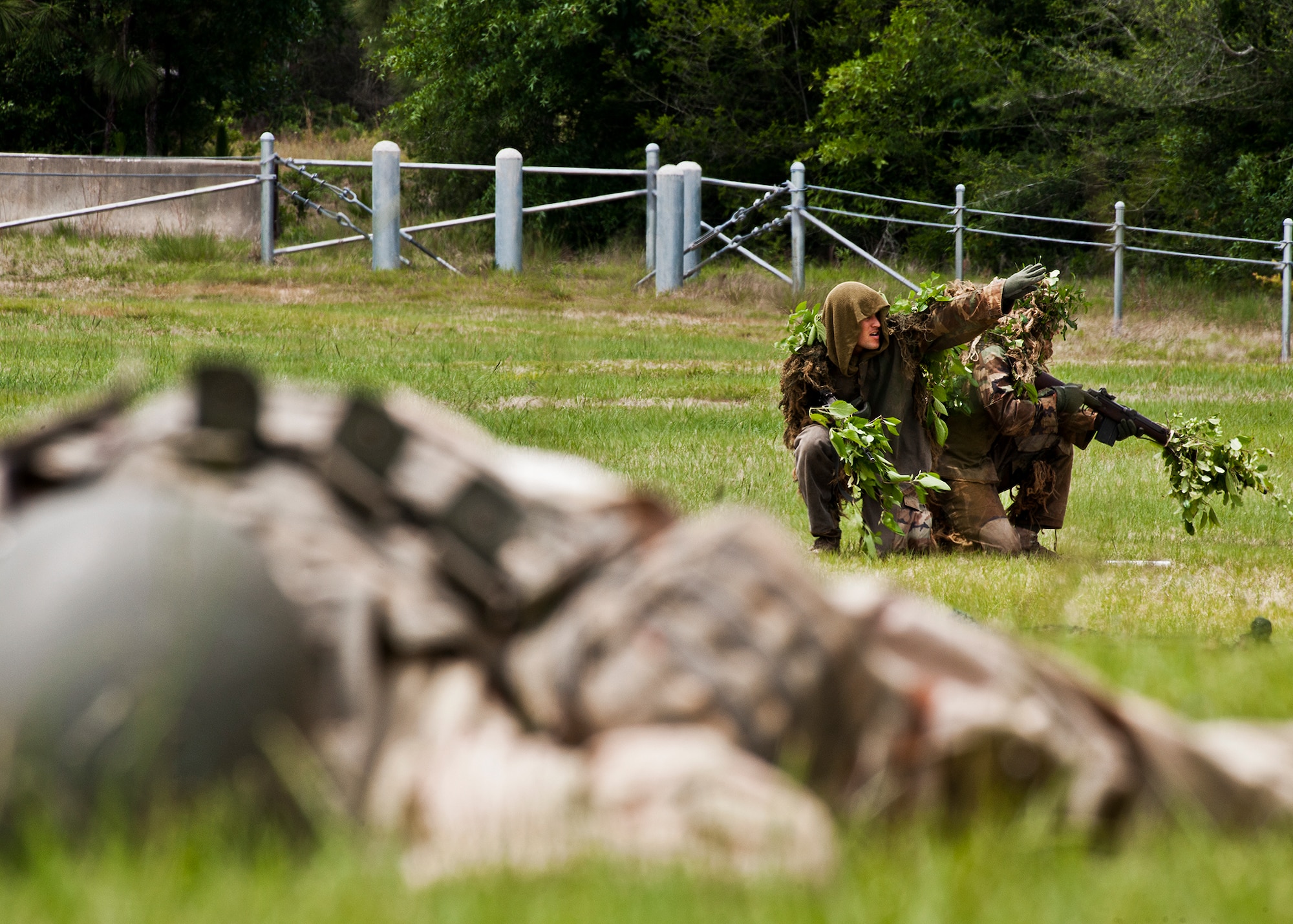 An “enemy” body lies in the foreground as a member of an Army Ranger sniper team throws a smoke grenade before helicopter extraction during a demonstration at the 6th Ranger Training Battalion’s annual open house event, May 12 at Eglin Air Force Base, Fla.  The event was a chance for the public to learn how Rangers train and operate. The event displays showed dive equipment, weapons, a reptile zoo and zodiac boats among others. The demonstrations showed off hand-to-hand combat, a parachute jump, a down-pilot scenario and others.  (U.S. Air Force photo/Samuel King Jr.)