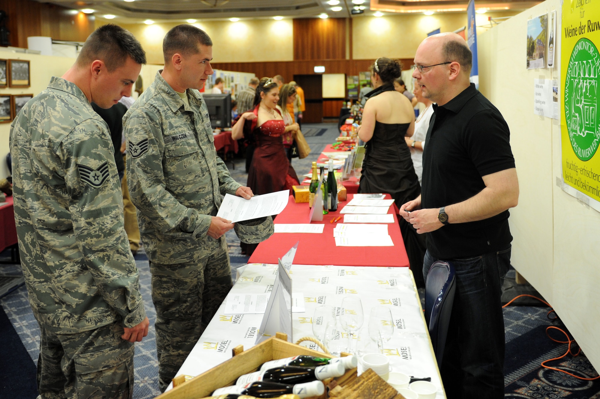 SPANGDAHLEM AIR BASE, Germany – Staff Sgt. Justin Mohr and Staff Sgt. Matthew Wilczek, 52nd Equipment Maintenance Squadron, speak with Marc Noel, a representative from the Von Nell wine-estate in Kasel, about signing up for a tour during the seventh annual Explore the Eifel fair at Club Eifel here May 11. The event had more than 200 exhibitors from Germany, Belgium and Luxembourg providing travel information on hiking trips and hot-air balloon rides, prizes, free samples, wine tastings, and more. This event gave attendees the chance to sign up for tours and adventures taking place May 18-20 in the Eifel area. (U.S. Air Force photo by Senior Airman Christopher Toon/Released)