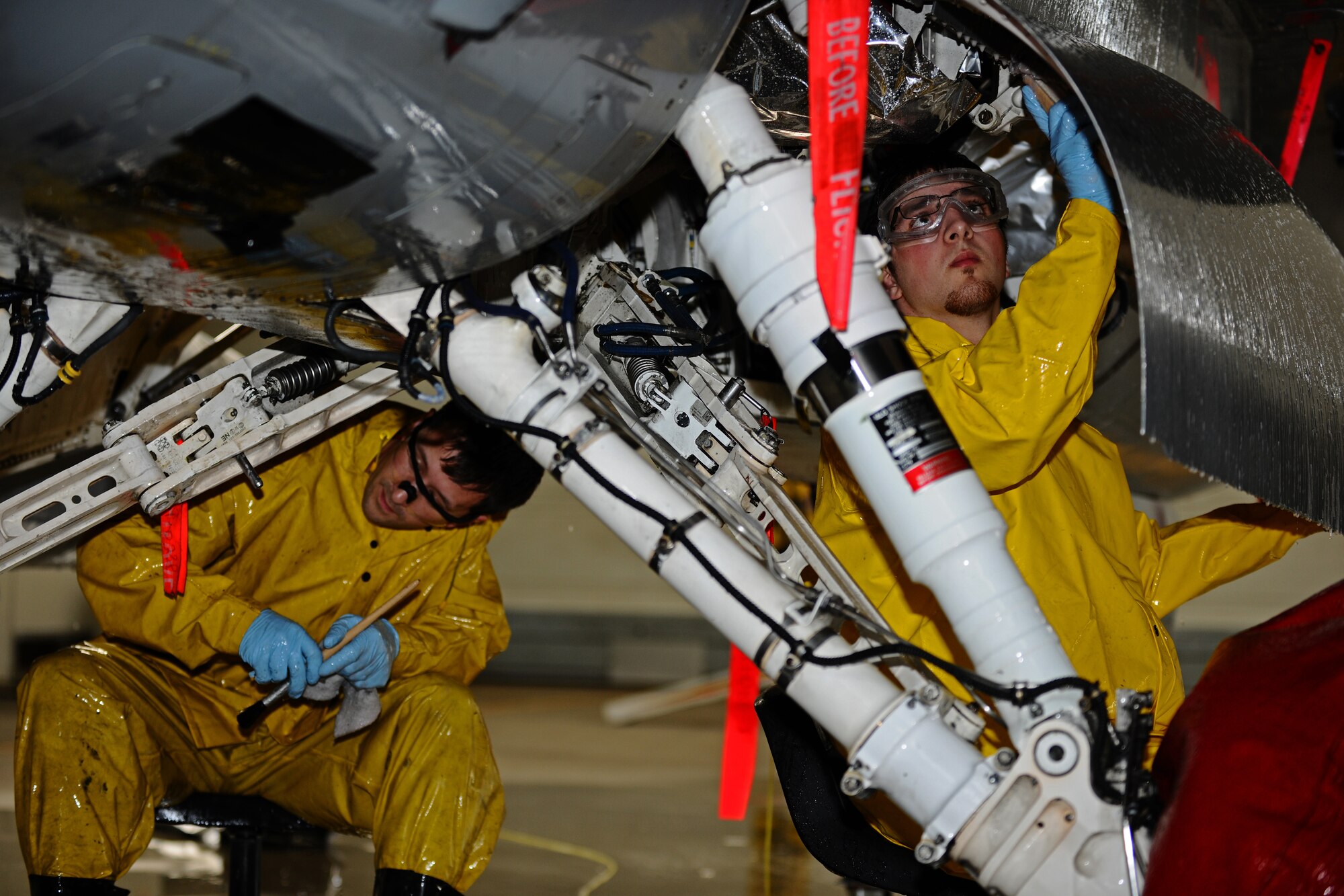 SPANGDAHLEM AIR BASE, Germany – Josh Larkin, left, and Adam Chapman, 52nd Equipment Maintenance Squadron Fabrication Flight corrosion control civilian contractors, clean the landing gear on an F-16 Fighting Falcon in Hangar 3 here May 11. The fabrication flight contractors wash every 52nd Fighter Wing aircraft twice a year to prevent corrosion and extend the lifespan of the aircraft. (U.S. Air Force photo by Airman 1st Class Matthew B. Fredericks/Released)