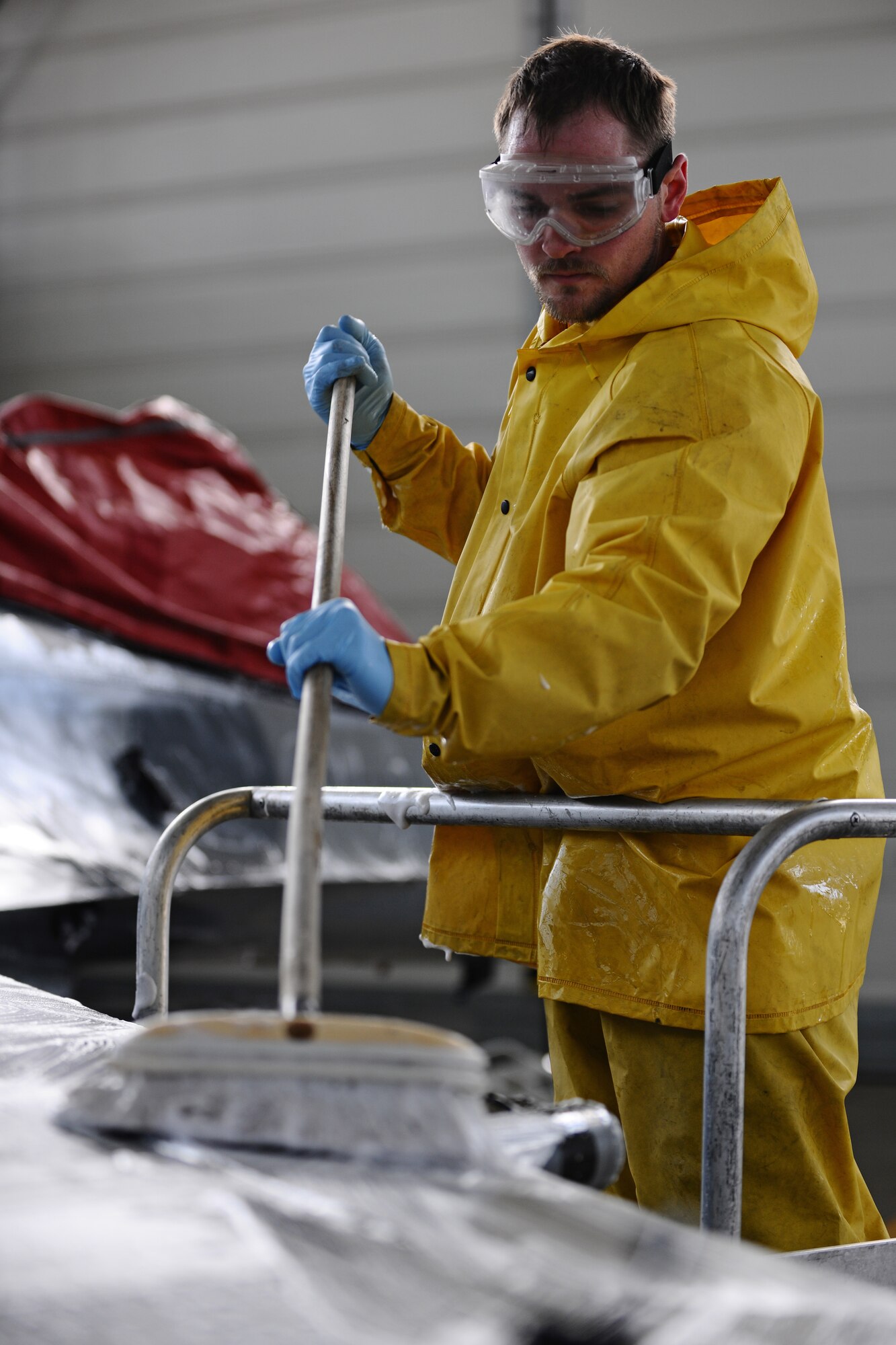 SPANGDAHLEM AIR BASE, Germany – Dustin Bowers, 52nd Equipment Maintenance Squadron Fabrication Flight corrosion control civilian contractor, cleans the wing of an F-16 Fighting Falcon with a brush in Hangar 3 here May 11. The fabrication flight contractors wash every 52nd Fighter Wing aircraft twice a year to prevent corrosion and extend the lifespan of the aircraft. (U.S. Air Force photo by Airman 1st Class Matthew B. Fredericks/Released)