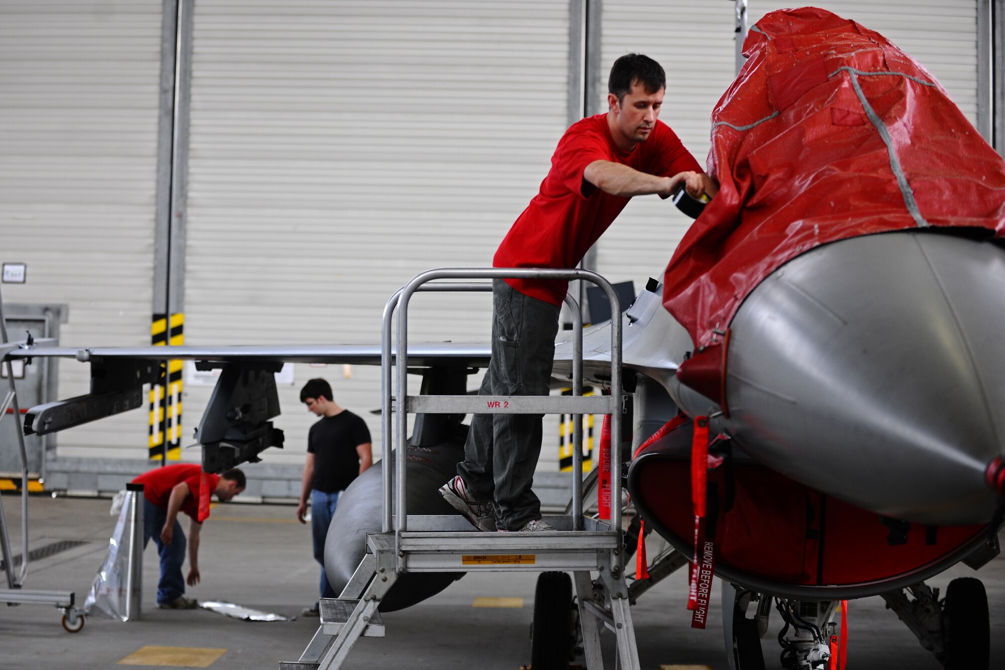 SPANGDAHLEM AIR BASE, Germany – Josh Larkin, 52nd Equipment Maintenance Squadron Fabrication Flight corrosion control civilian contractor, covers the canopy of an F-16 Fighting Falcon before washing it in Hangar 3 here May 11. The fabrication flight contractors wash every 52nd Fighter Wing aircraft twice a year to prevent corrosion and extend the lifespan of the aircraft. (U.S. Air Force photo by Airman 1st Class Matthew B. Fredericks/Released)