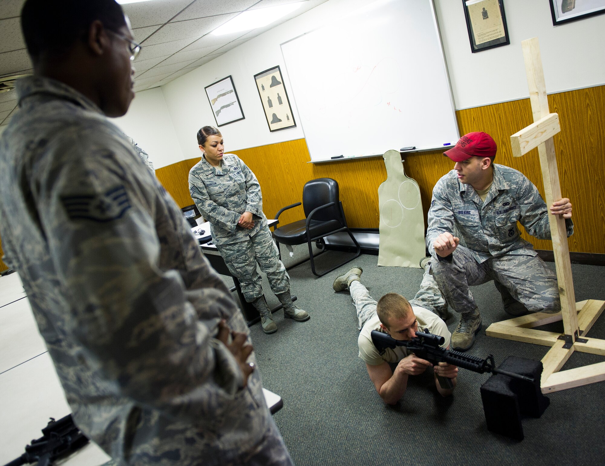 YOKOTA AIR BASE, Japan -- Senior Airman Rodney Wilkins, 374th Security Forces Squadron combat arms training and maintenance instructor, right, demonstrates proper shooting techniques with an M4 rifle to Staff Sgt. Ljavar Fludd-Moss, 374th Communications Squadron radio frequency transmissions specialist, left, and Staff Sgt. Raquel Johnson, 374th Force Support Squadron guest services manager, before shooting on the range May 10, 2012, at Yokota Air Base, Japan. Each student must attend training in a classroom environment before shooting on the range. (U.S. Air Force photo by Staff Sgt. Chad C. Strohmeyer)