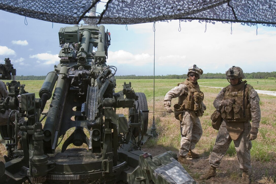 Private First Class Dwight Smith Jr. (left), cannoneer, gun 2, Battery L, 3rd Battalion, 10th Marine Regiment, tugs on the pull cord as he receives the order to fire the M777 Howitzer.  The 2nd Marine Division Marine, and Richmond, Va., native, said that being a part of a cannoneer section is the best example there is of Marine adaptation and efficiency.