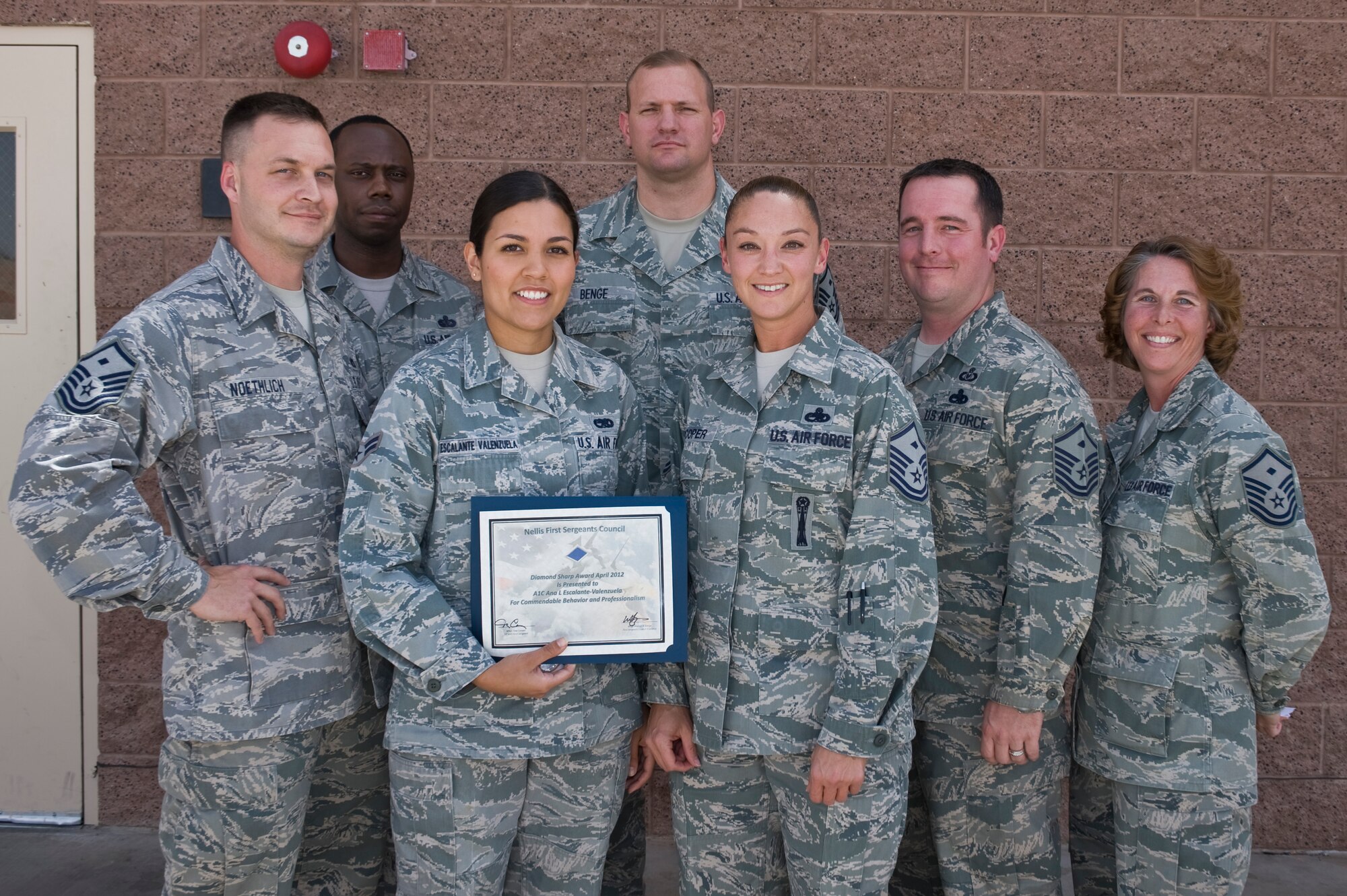 U.S. Air Force Master Sgt. Tina Cooper, 57th Test and Evaluations Group first sergeant, presents the Diamond Sharp Award to Airman 1st Class Ana Escalante-Venezuela, 57th Maintenance Squadron small bombs crew member, as members of the first sergeants council look on May 10, 2012, at Nellis Air Force Base, Nev. The First Sergeant's Diamond Sharp Award is designed to recognize an individual who truly stands out with abilities, sheer drive and characteristic traits most others do not possess. Escalante-Valenzuela was hand picked to serve on the Nellis AFB Honor Guard and has performed over 57 details.
 (U.S. Air Force photo by Airman 1st Class Daniel Hughes)

