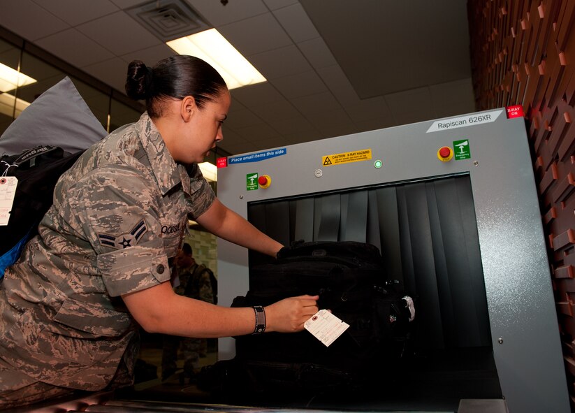 Airman 1st Class Donna Woodside, 28th Aircraft Maintenance Squadron aircraft electrician, puts her luggage onto an x-ray conveyer belt to be scanned by transportation safety administration in preparation to leave for Green Flag, a combat training exercise at Nellis Air Force Base, Nev., in the deployment center at Ellsworth AFB, S.D., May 10, 2012. The x-ray machine allows Airmen performing TSA duties to confirm that all luggages being loaded onto an aircraft is hazard free. (U.S. Air Force photo by Airman 1st Class Kate Thornton/Released)